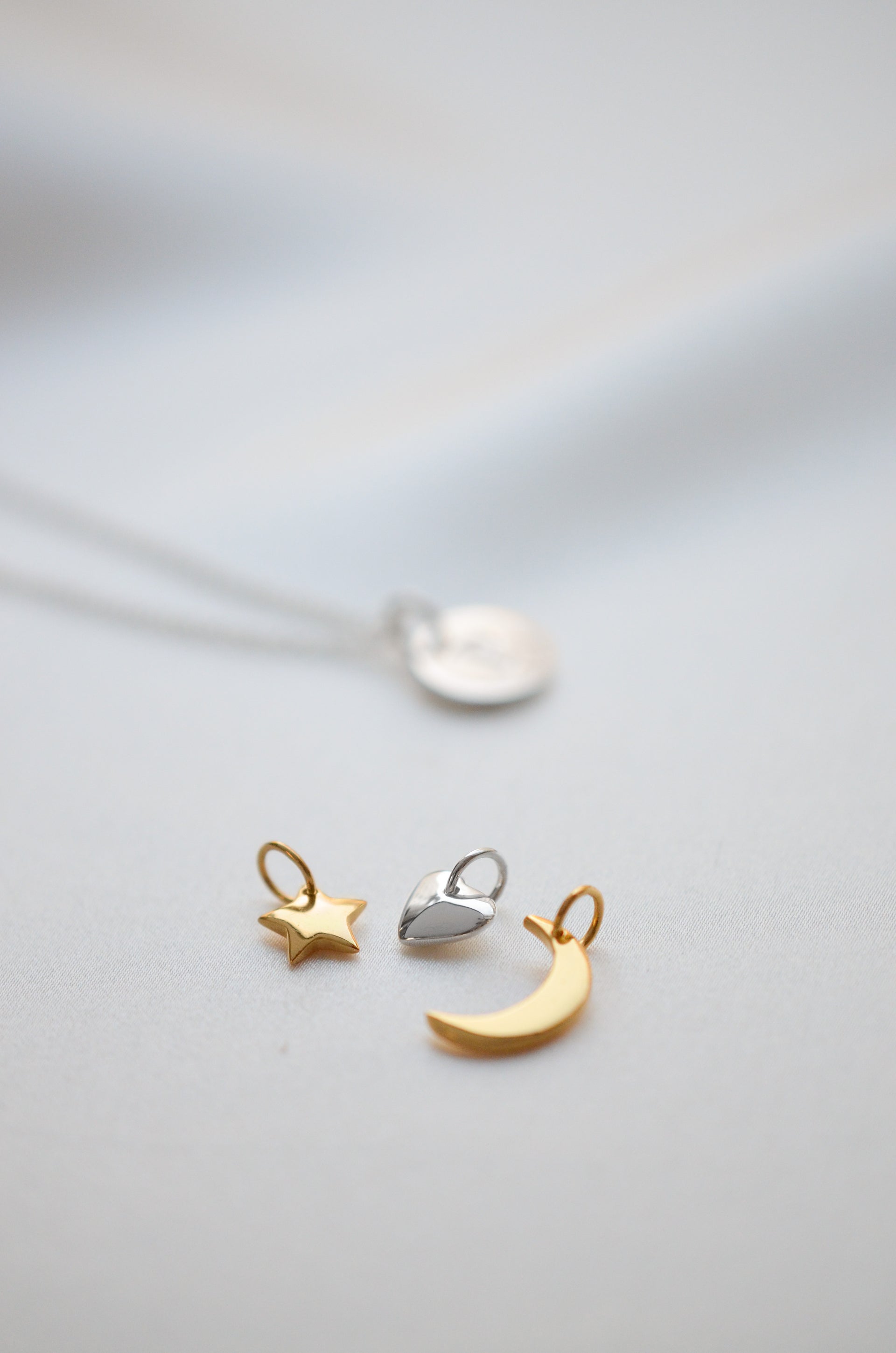 Gold star pendant, gold moon pendant and silver heart pendant styled together