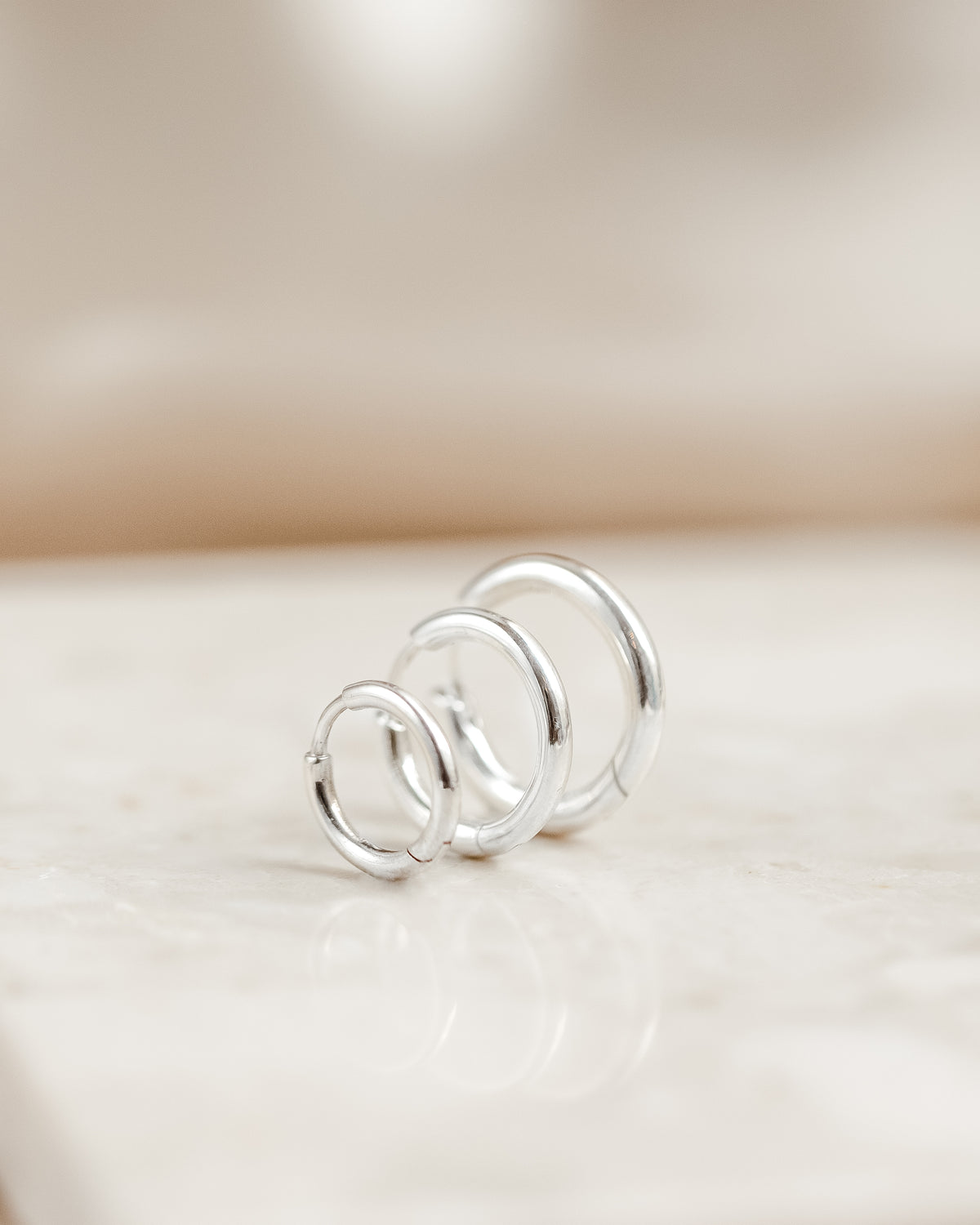 A product shot of the Beloved Fat Hoops in silver, displaying three different sizes arranged in a row to highlight their thick, rounded design.