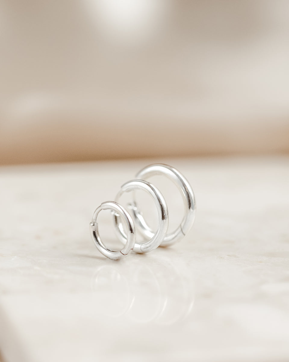 A product shot of the Beloved Fat Hoops in silver, featuring three different sizes arranged in a row to display their classic, chunky design.
