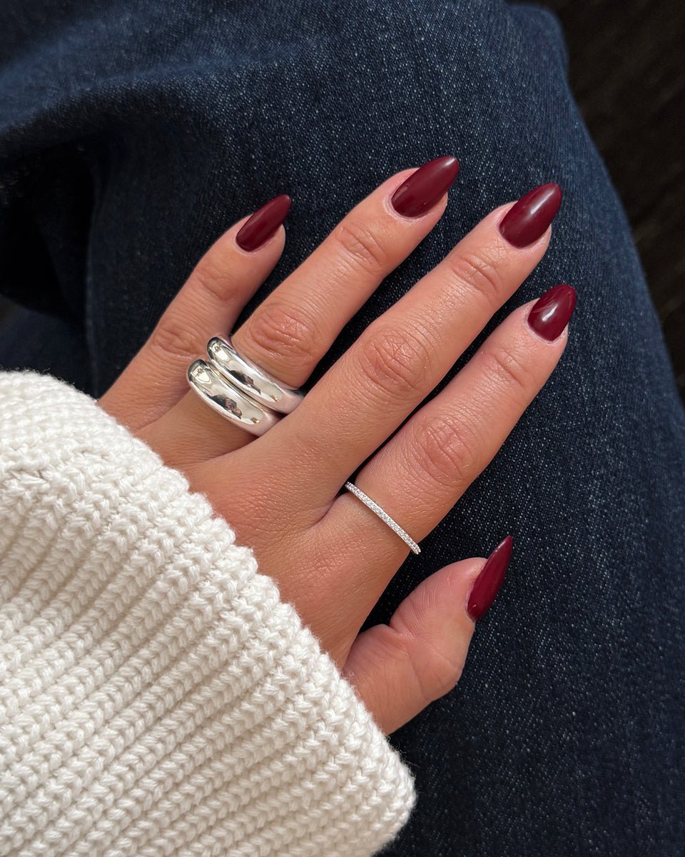A model wears the Tiny Sparkle Ring Silver, a delicate eternity band, on her ring finger, styled with a bold, double-banded silver ring on her index finger.