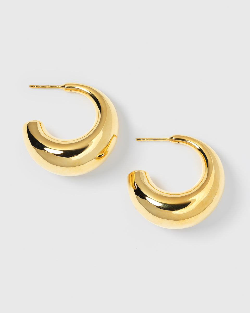 A product shot of the Bolded Earrings in gold, a pair of chunky, crescent-shaped hoops with a polished finish.