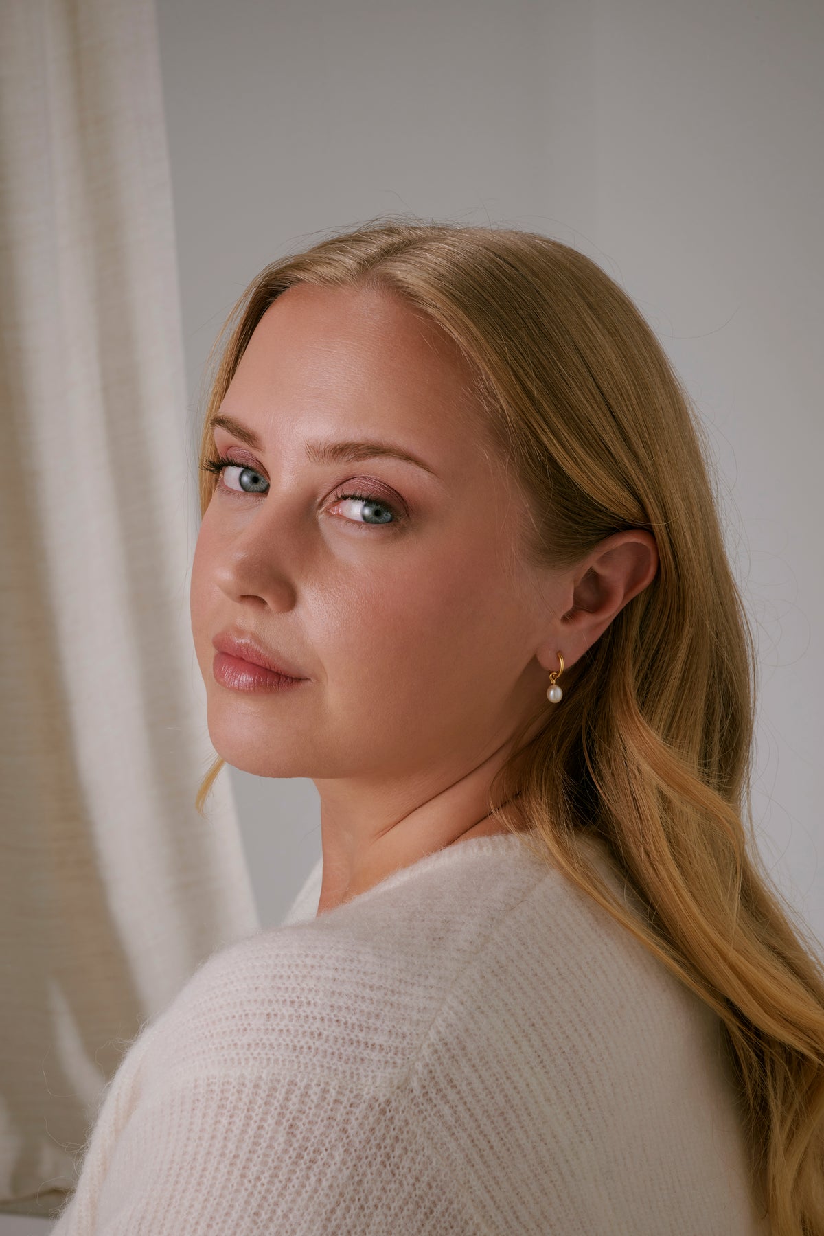 A shot of a model wearing the Treasure Pearl Hoops Gold, featuring a dangling freshwater pearl.