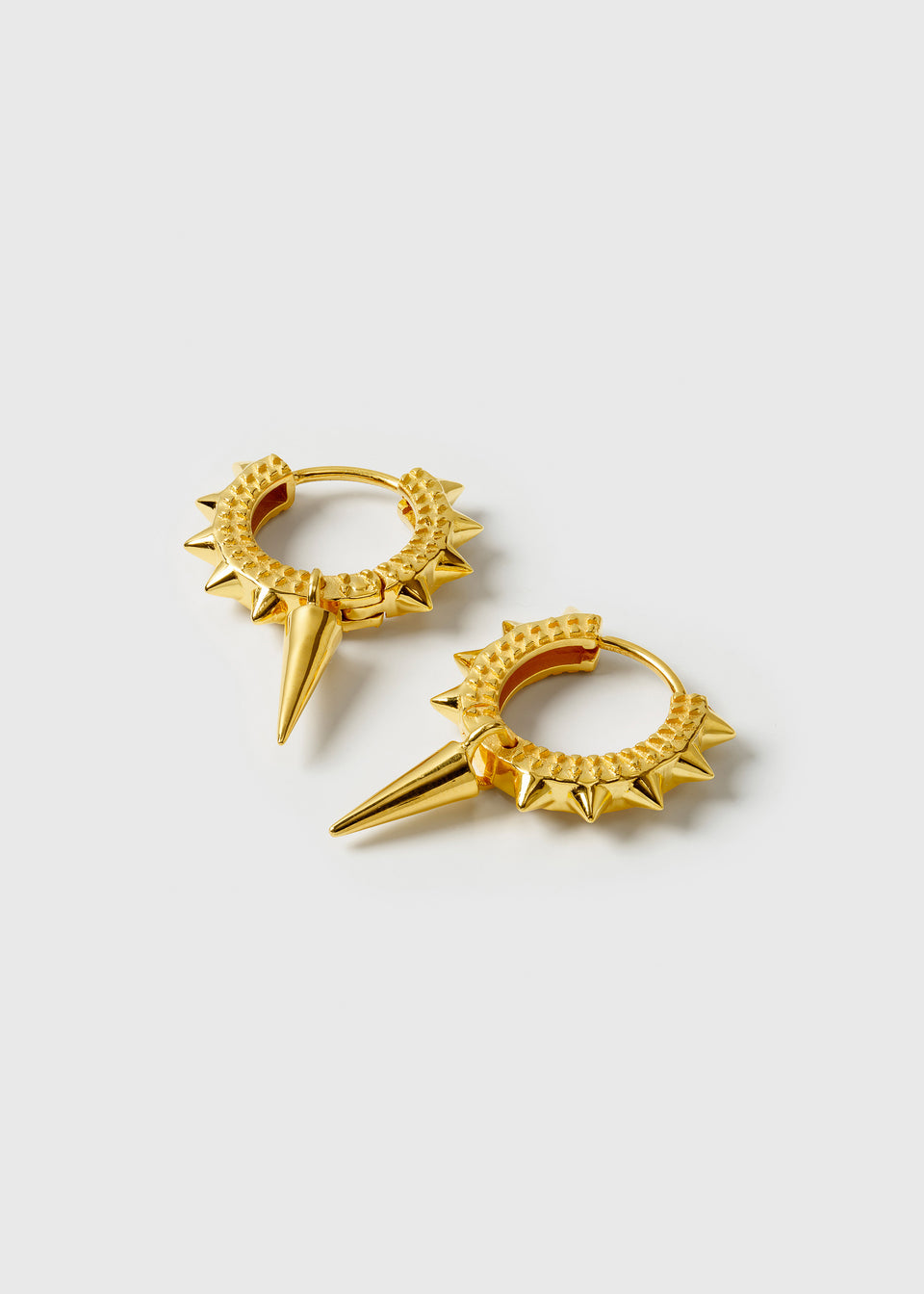 A product shot of the Harvey Heavy Spike Hoops in gold, showcasing their textured finish, small surrounding spikes, and a single prominent hanging spike on each earring.