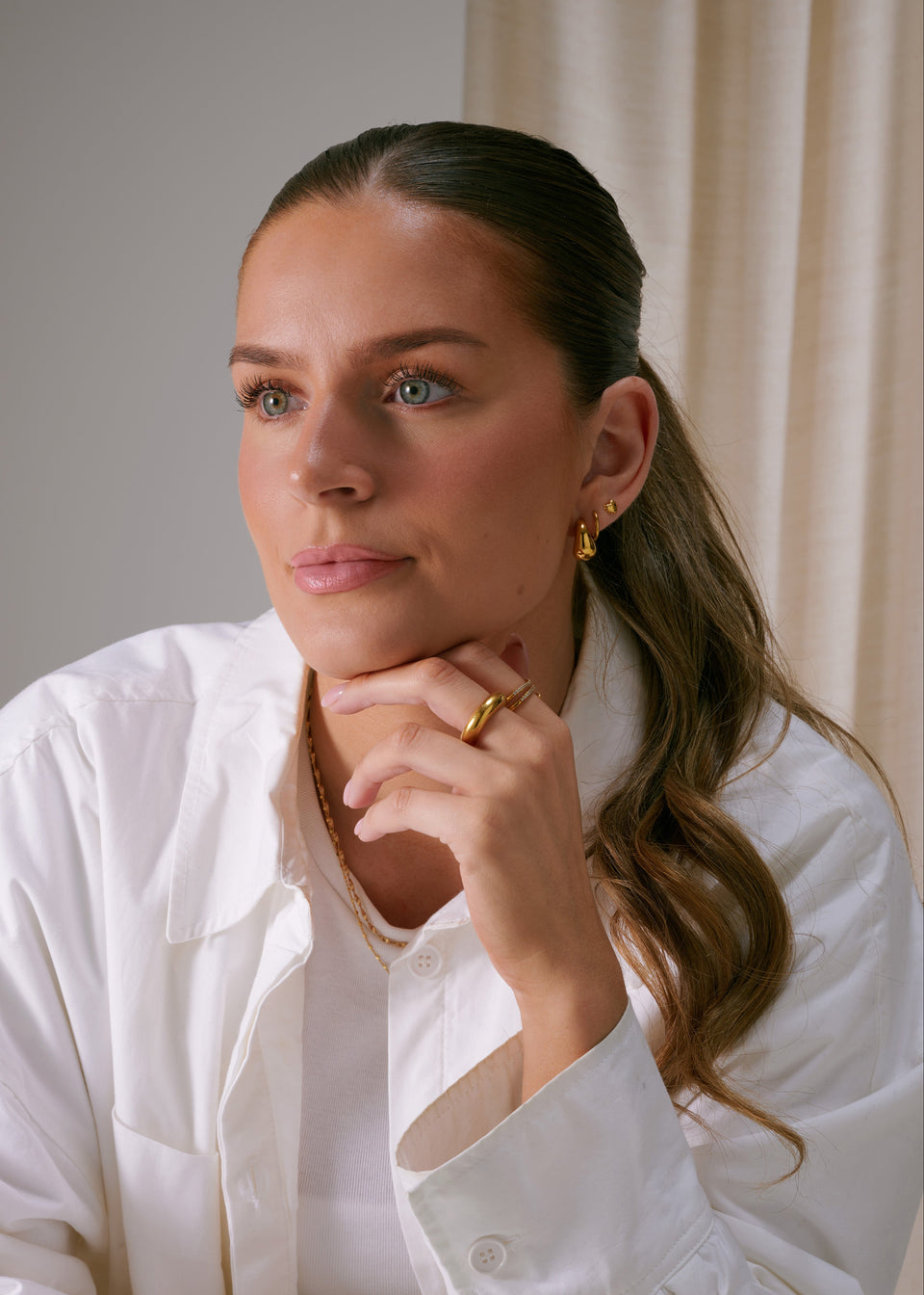 Drop-shaped earrings, a matching chunky gold ring, and a delicate gold chain necklace.