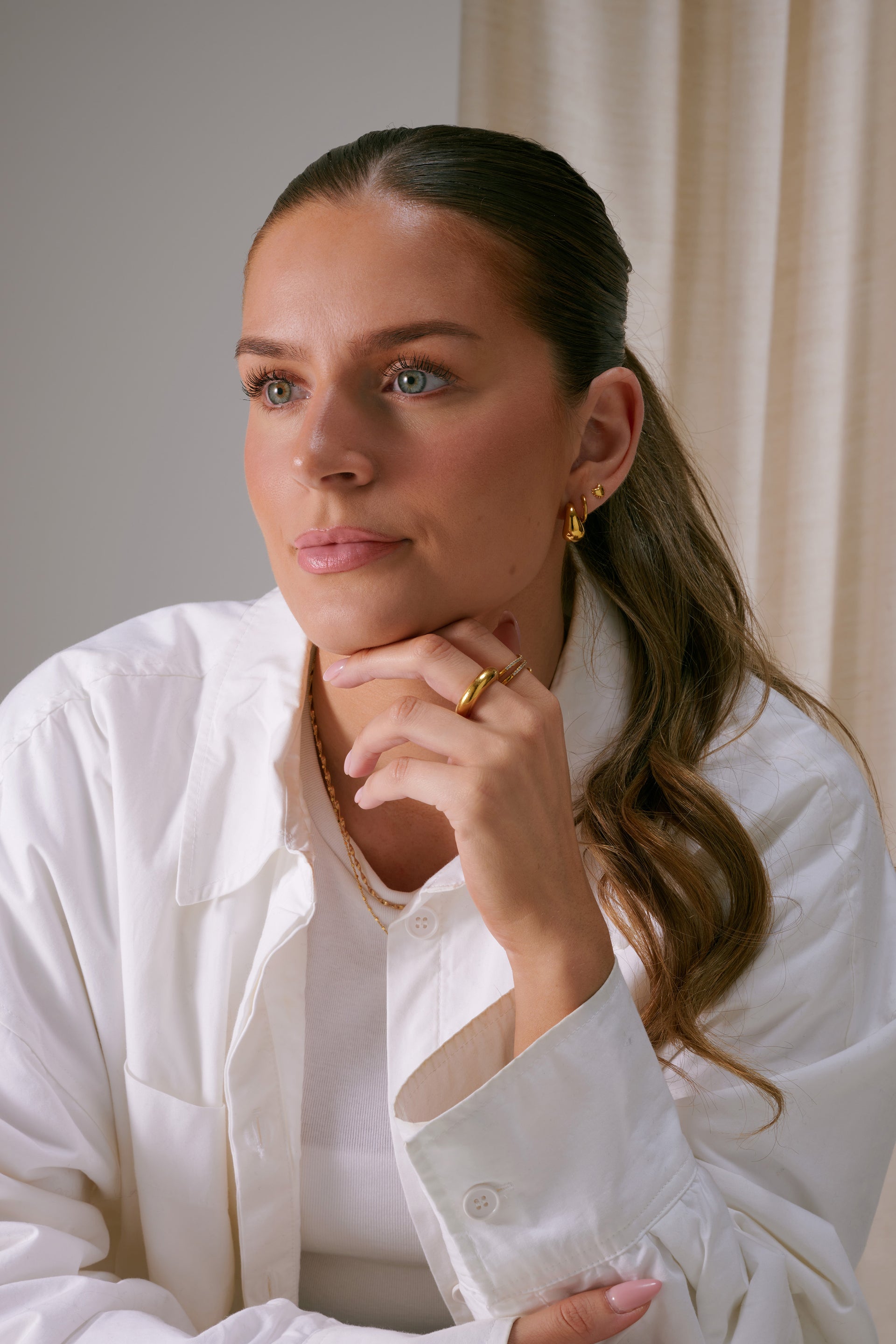 A image of a model wearing the True Love Spike Heart Studs in gold, showing the small heart-shaped earring with spike details on her earlobe.