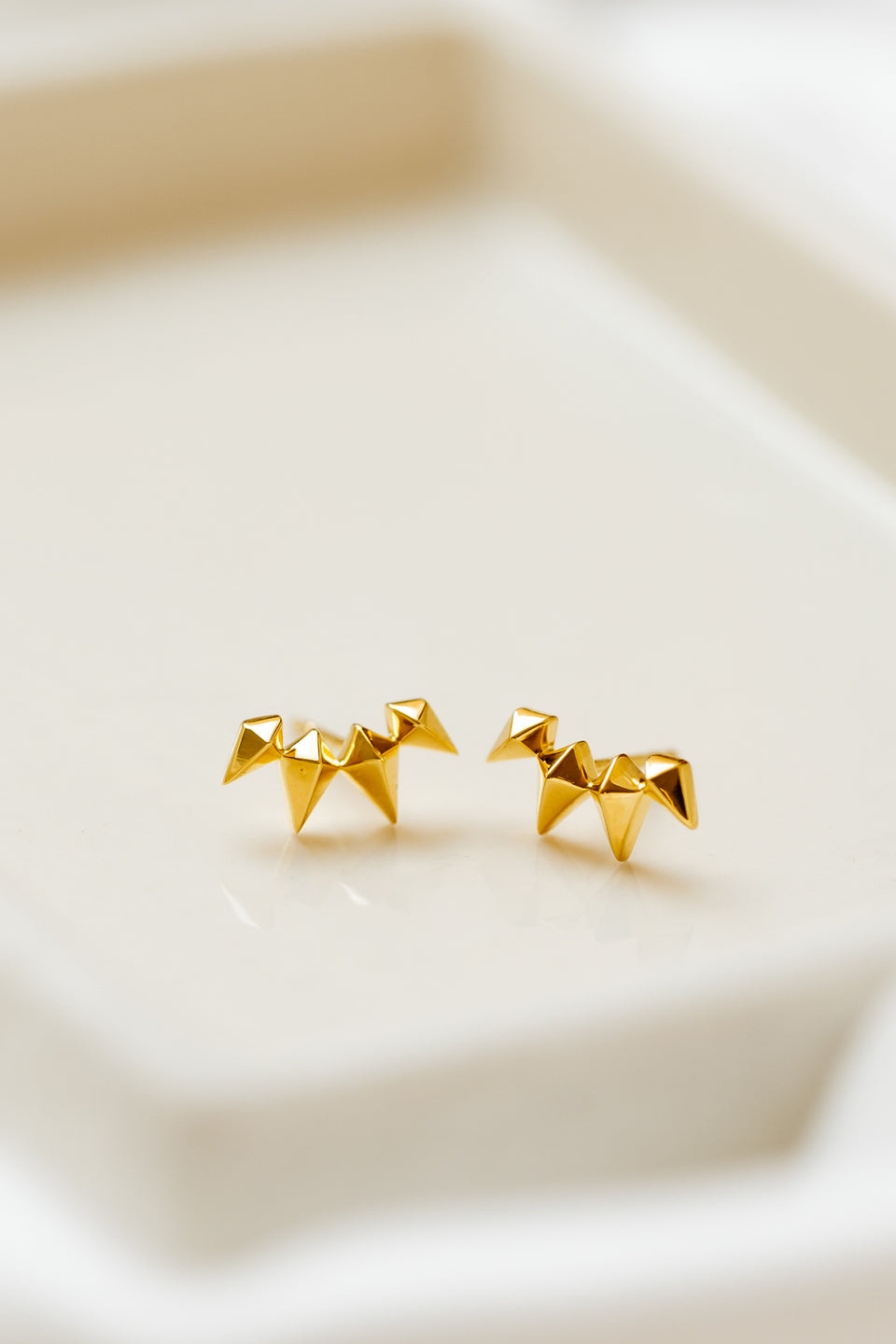 A product shot of the Uma Climber Earrings in gold, displayed side-by-side to showcase their design composed of small, geometric spikes.