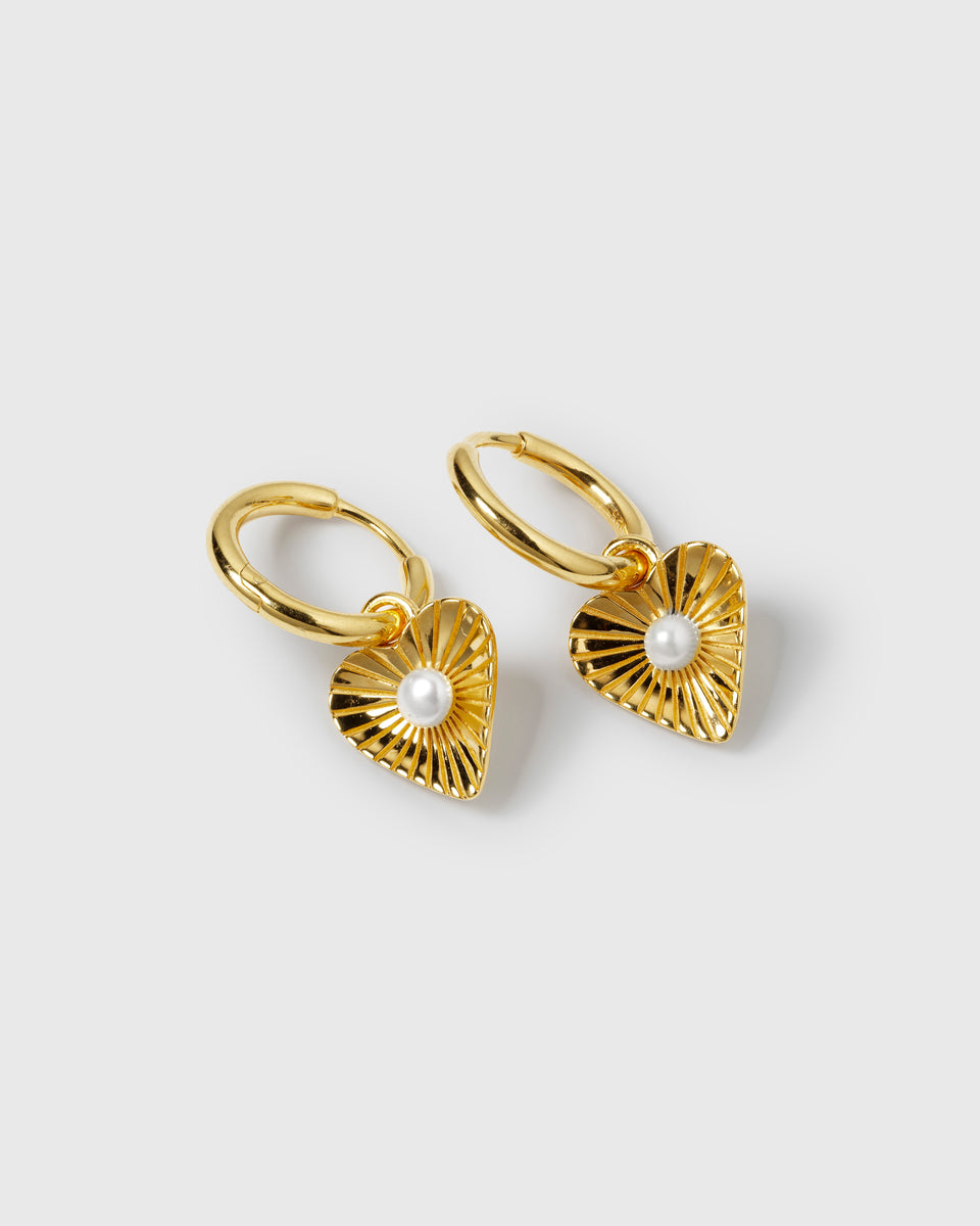 A product shot of the gold Aurelia Earrings, featuring hoop earrings with a textured, heart-shaped pendant and a central freshwater pearl.
