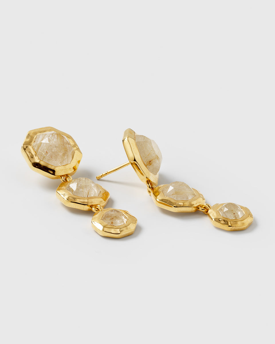 A product shot of the RENTAL - Octagon Earrings Gold, showcasing the pair of long, dangling earrings, each featuring three unique, octagon-shaped golden rutile quartz stones.