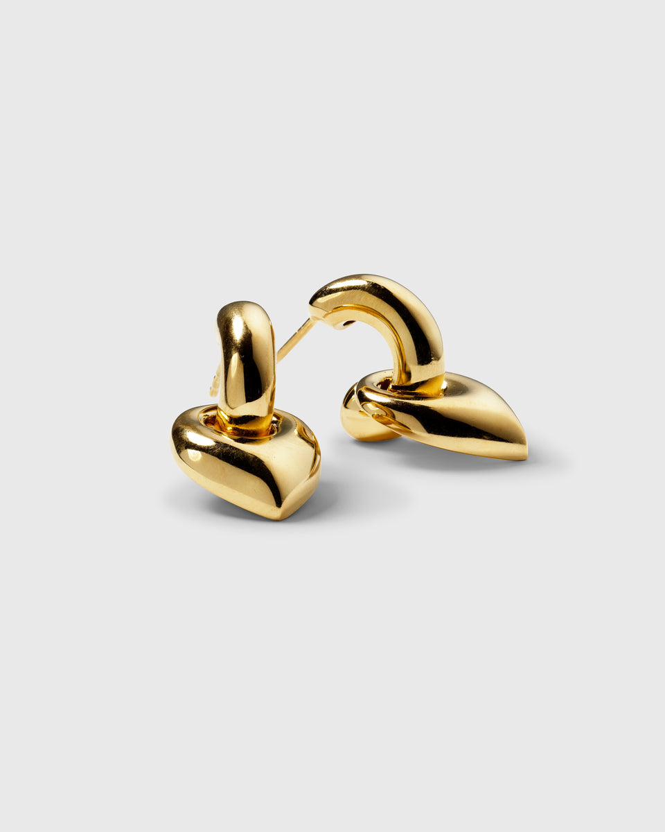 A product shot of the Melinda Earrings in gold, featuring a chunky hoop design with a bold, leaf-shaped pendant.