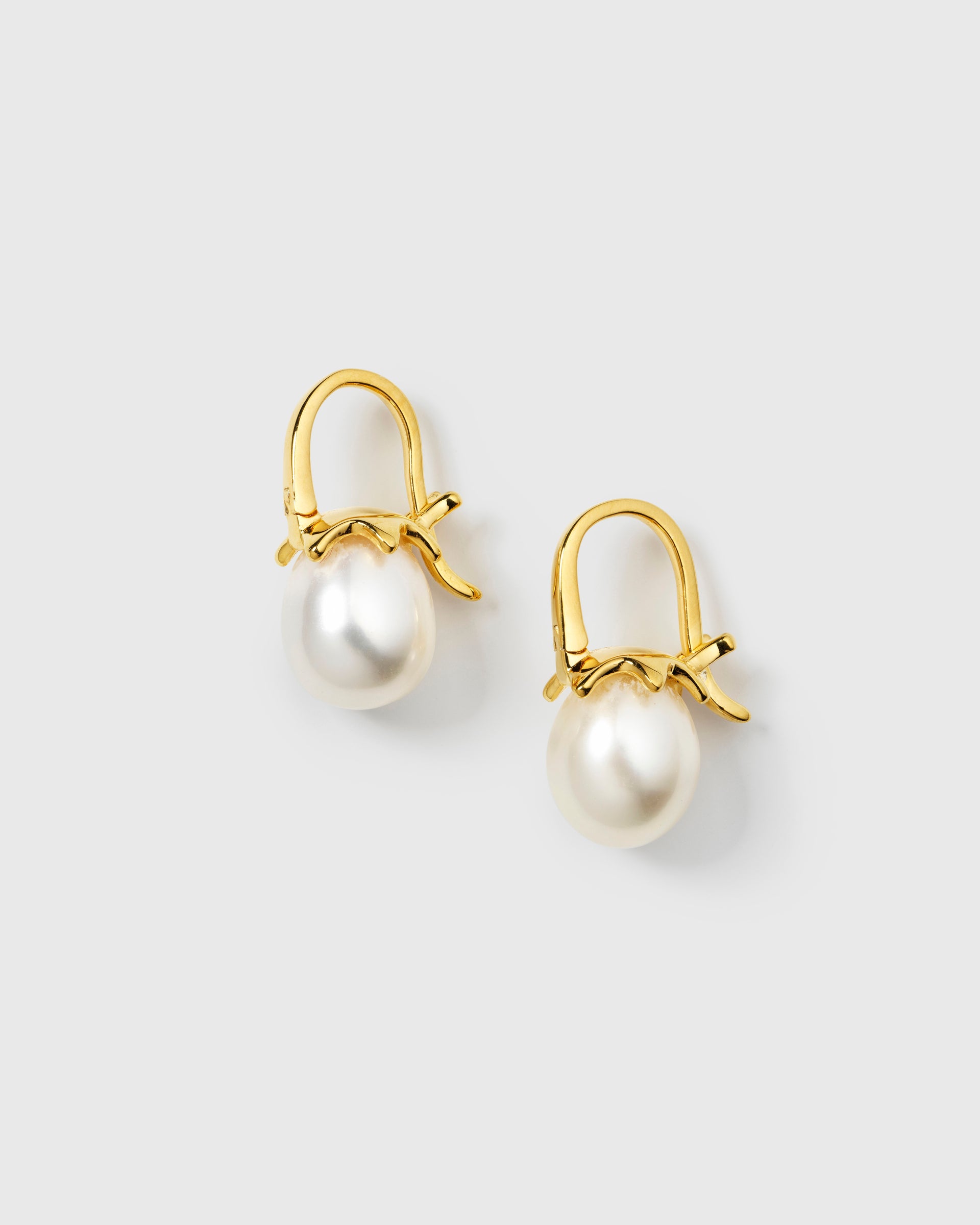 A pair of gold hoops with white freshwater pearls hanging from small, delicate bow details.