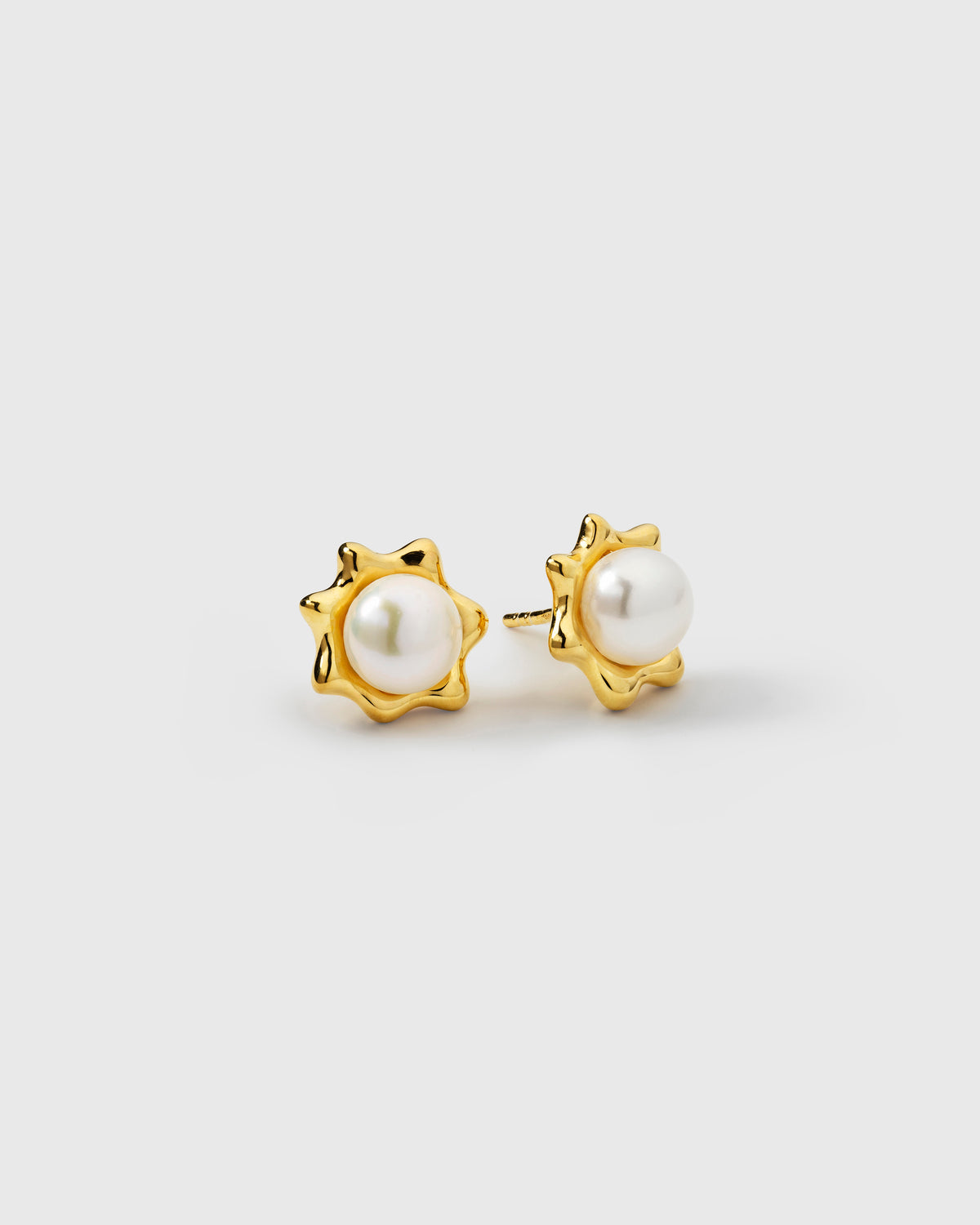 Delicate gold studs featuring white freshwater pearls in a sun-inspired design