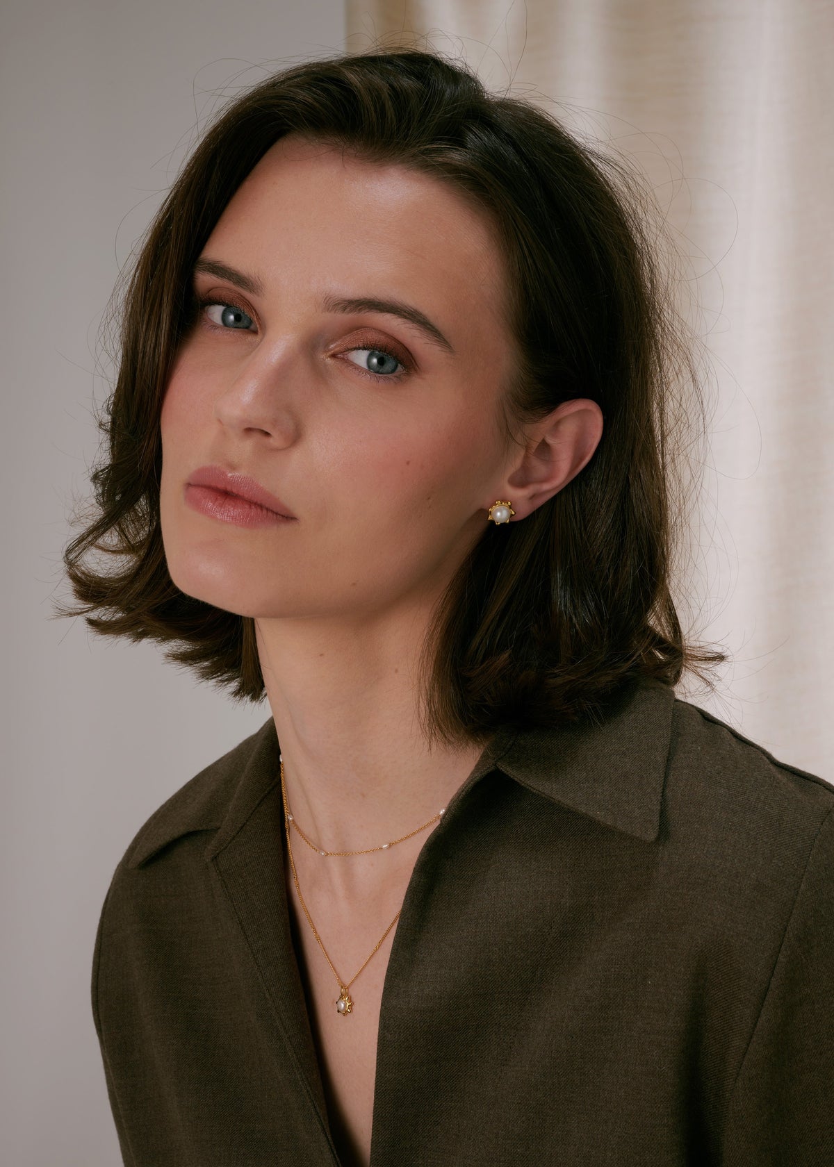 Gold stud earrings with a central freshwater pearl in a floral design, paired with a layered gold necklace—one chain with a matching freshwater pearl pendant and a shorter delicate chain with freshwater pearls.