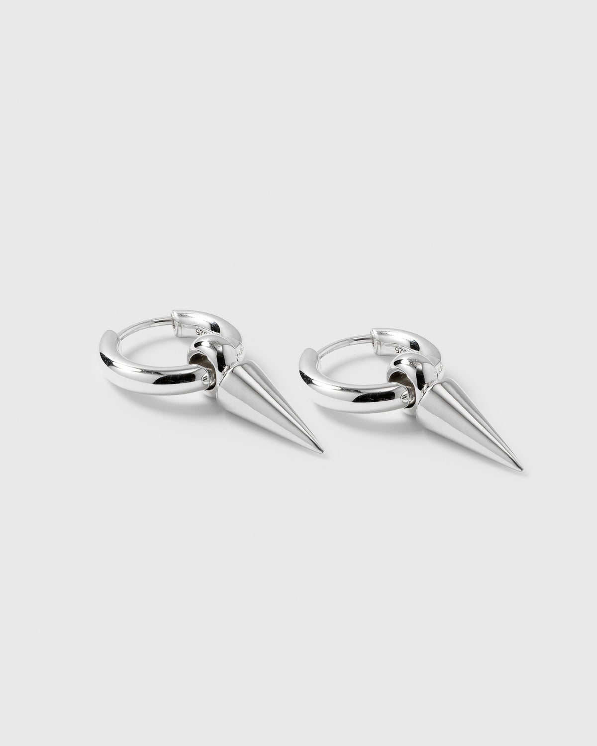 A product shot of the Juno Hoops in silver, featuring a pair of hoop earrings each with a dangling spike charm.