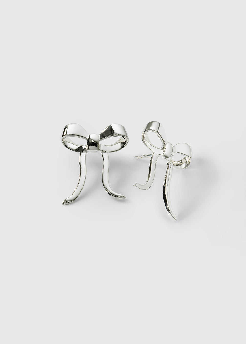 A product shot of the Rosie Earrings in silver, featuring their polished, three-dimensional bow design.