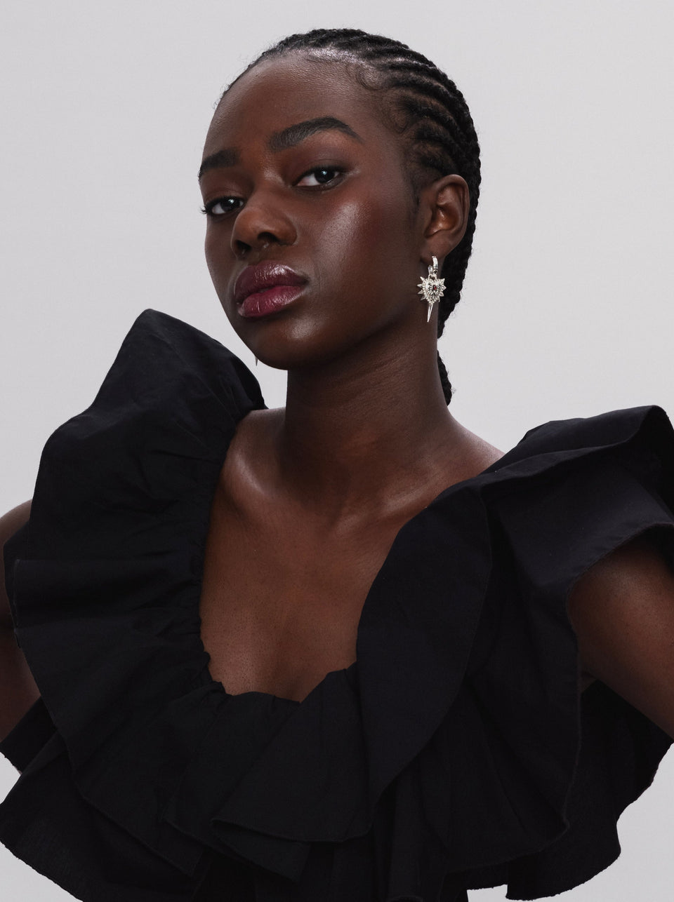 A model wearing the Drama Queen Heart Spike Earring in silver, featuring an edgy heart-shaped pendant with spikes dangling from a hoop.