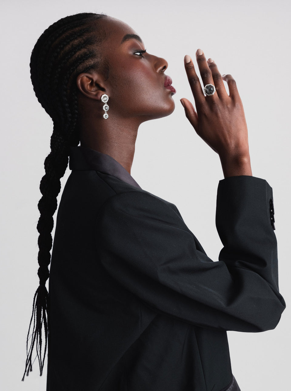 A profile shot of a model wearing the Octagon Ring in silver with a large black rutile stone and the matching dangling Octagon Earrings.