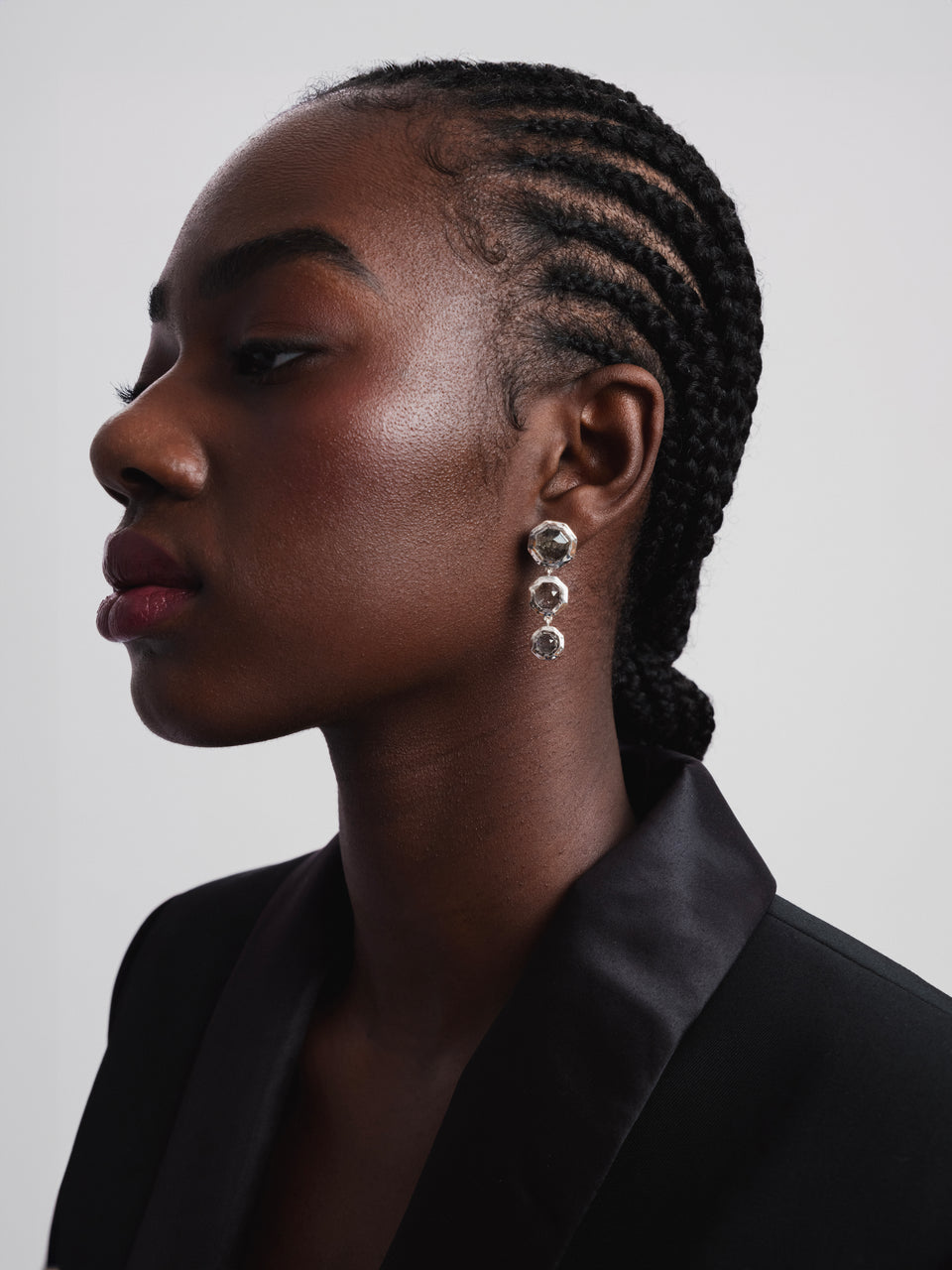 A close-up shot of a model wearing the Octagon Earrings in silver, which feature a drop design with three octagon-shaped black rutile quartz stones.