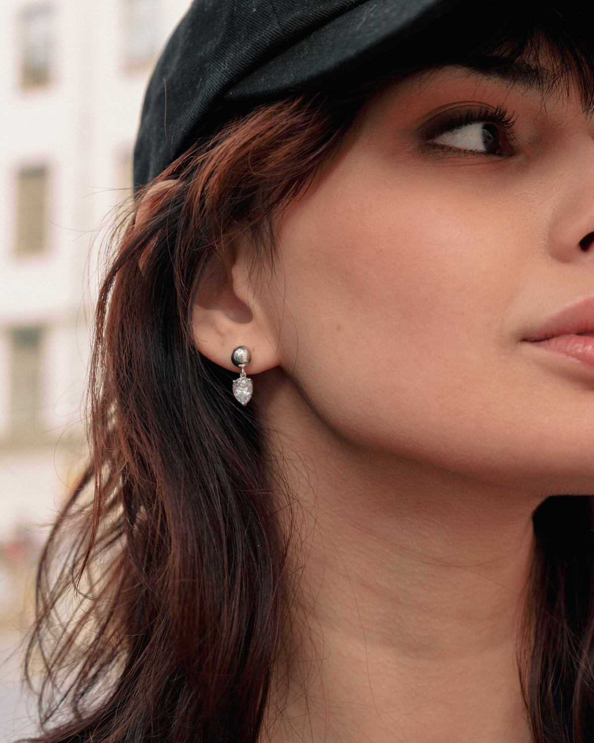 A close-up shot of a model wearing the Katie Earrings in silver, featuring a dangling drop-shaped cubic zirconia.