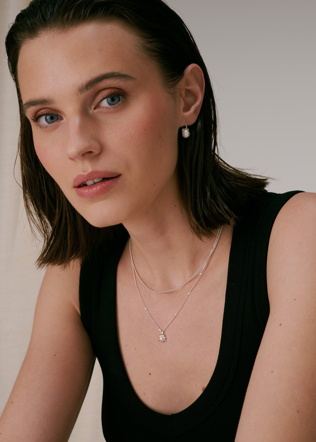 Silver freshwater pearl earrings with layered silver necklaces, one beaded and one with a small freshwater pearl.