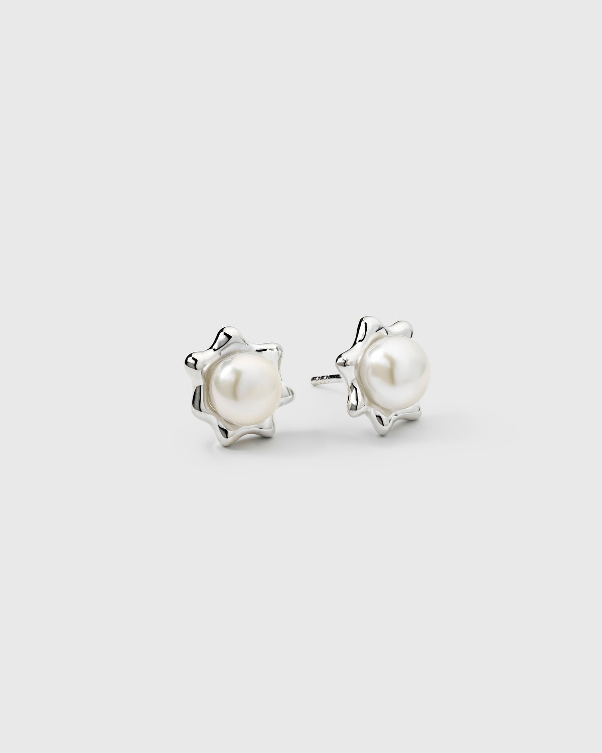 Silver star stud earrings featuring round freshwater pearls.