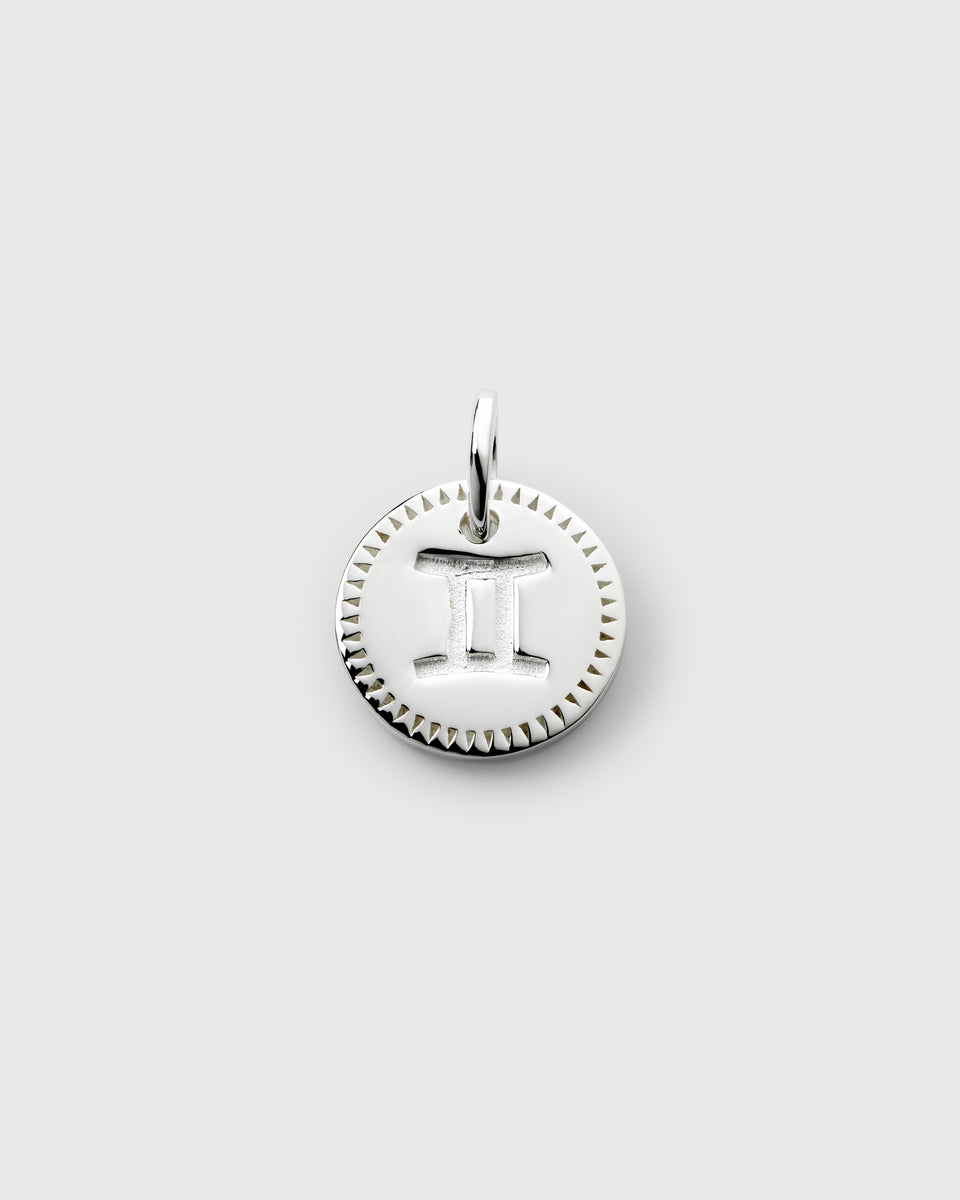 A product shot of the Beloved Zodie Pendant in silver, featuring the engraved zodiac symbol for Gemini on a round charm with a decorative border.