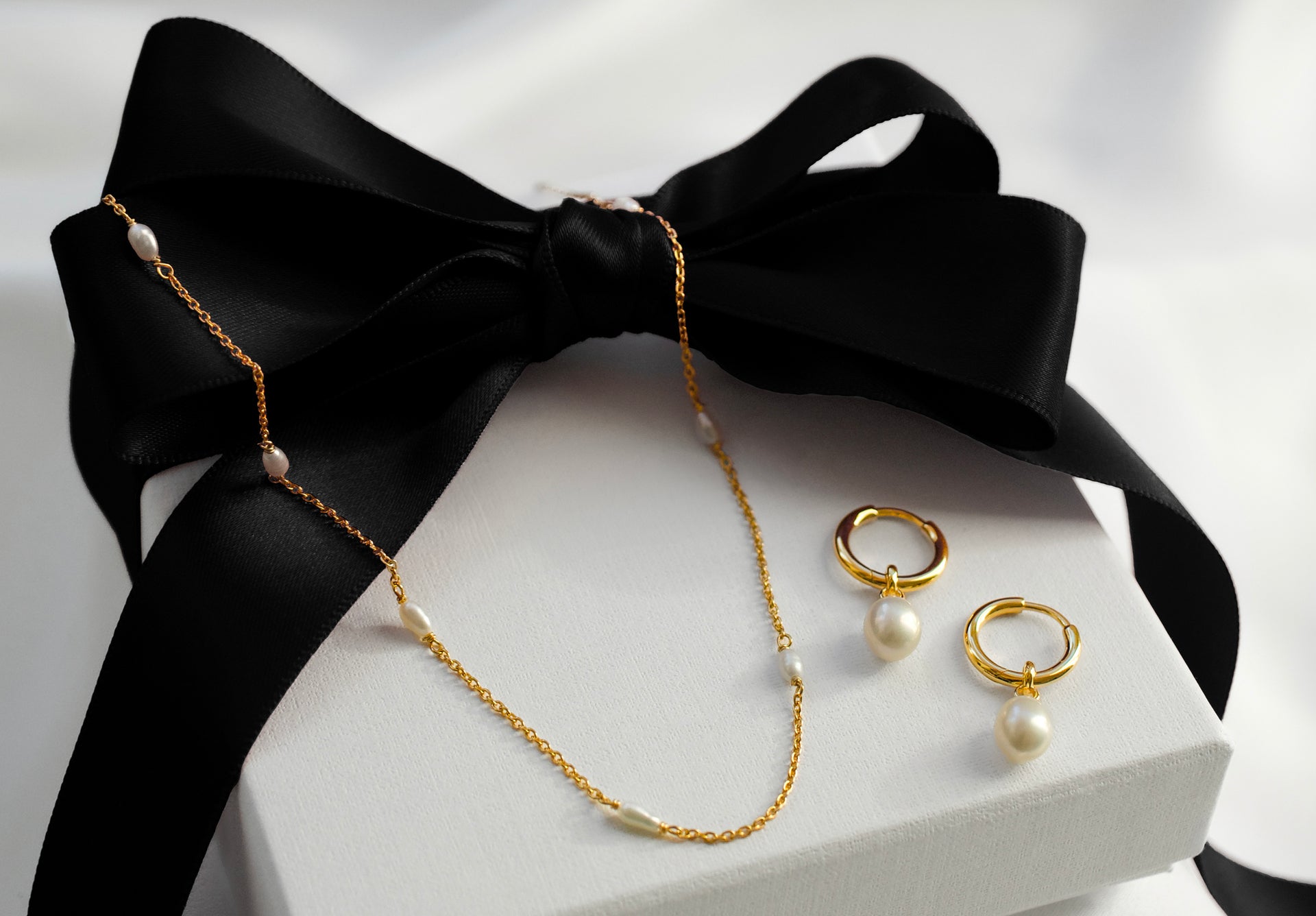 A necklace and earrings with fresh water pearls on top of a giftbox.