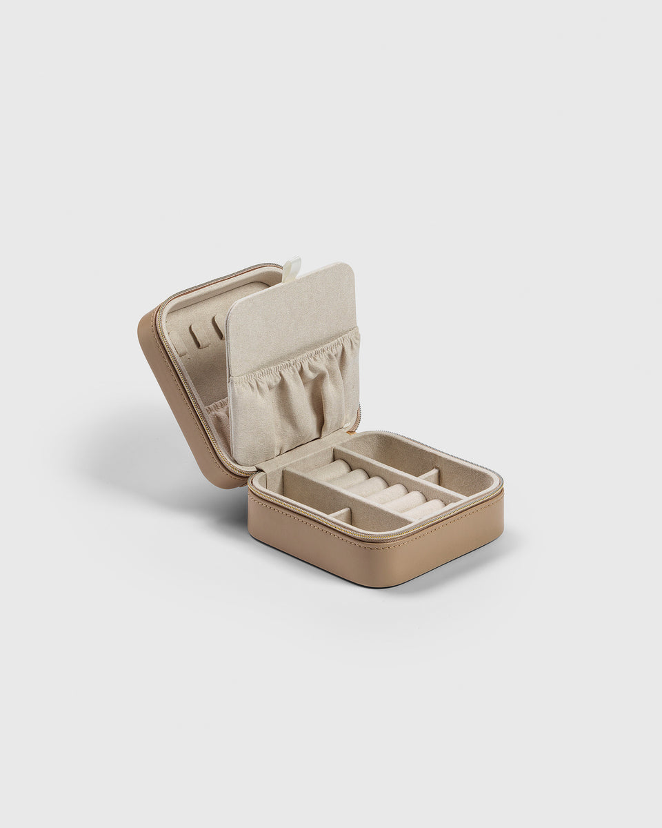 A product shot of the Small Jewelry Case in beige, open to reveal its organized interior with ring rolls, compartments, and a pouch in the lid.