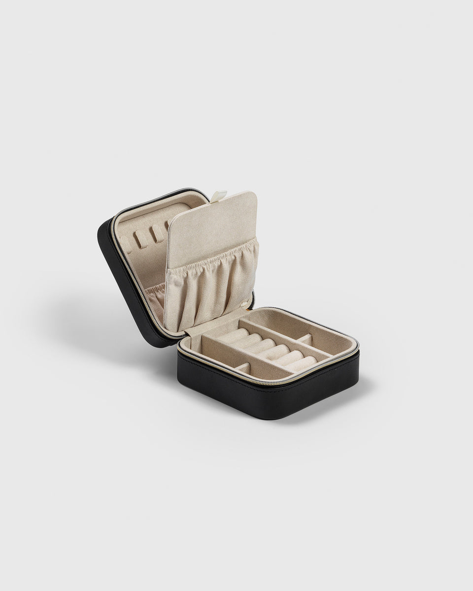 A product shot of the Syster P Jewelry Case Small Black, open to display its soft beige microfiber interior, which includes padded rolls for rings, small compartments, and pockets in the lid for organized storage.