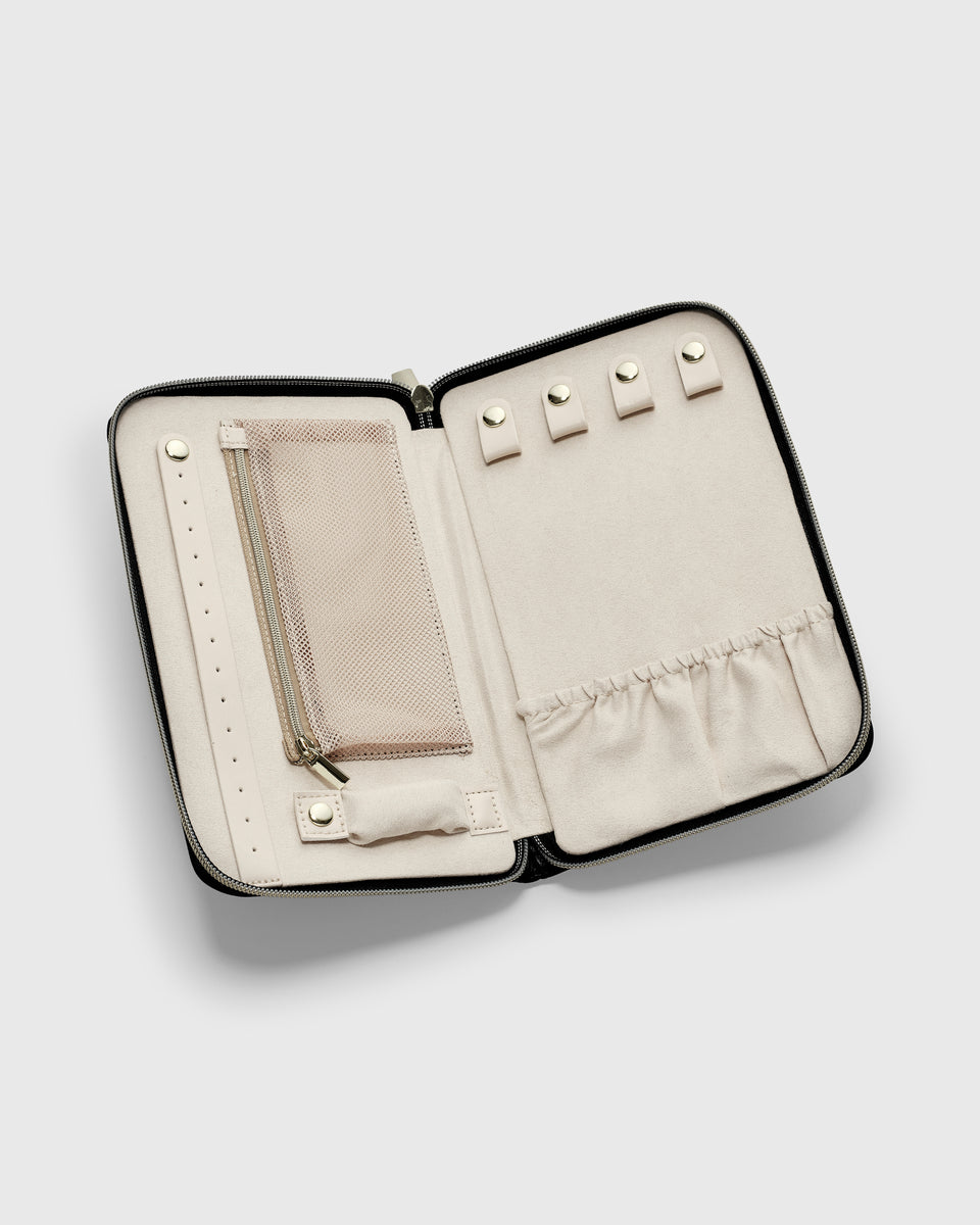 A product shot of the black Jewelry Travel Case, open to display its beige microfibre interior with multiple compartments for organizing rings, necklaces, and earrings.