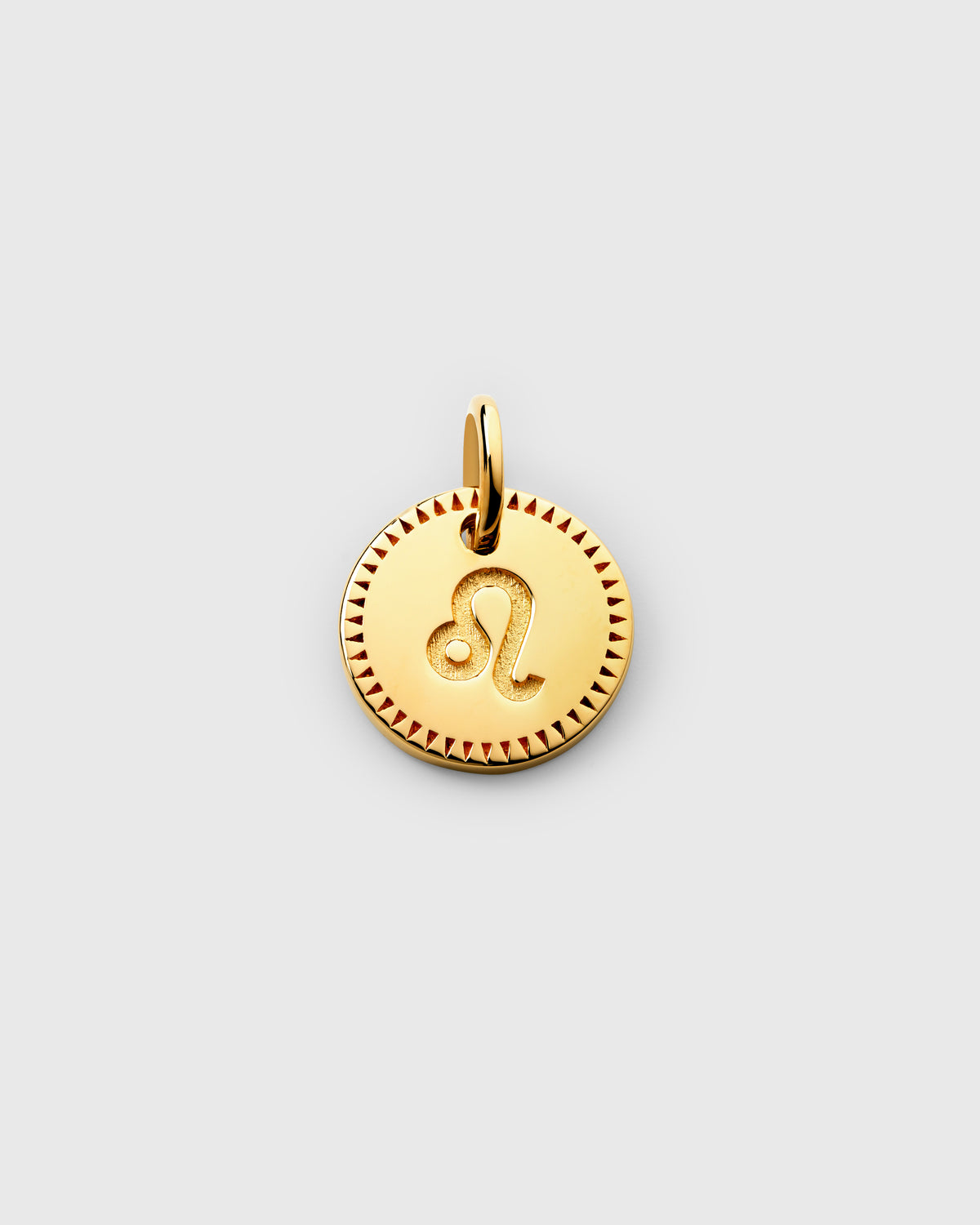 A product shot of the Beloved Zodie Pendant in gold, featuring the Leo zodiac sign engraved in the center of the round charm, which is framed by a decorative triangular border.