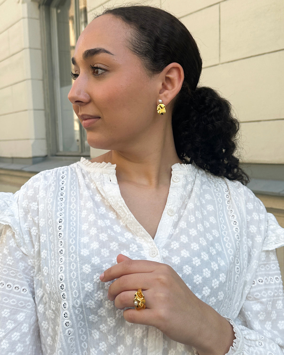 A model wearing the Moulded Short Earrings in gold, featuring an organic shape and a freshwater pearl, paired with the matching Moulded Big Ring in gold.