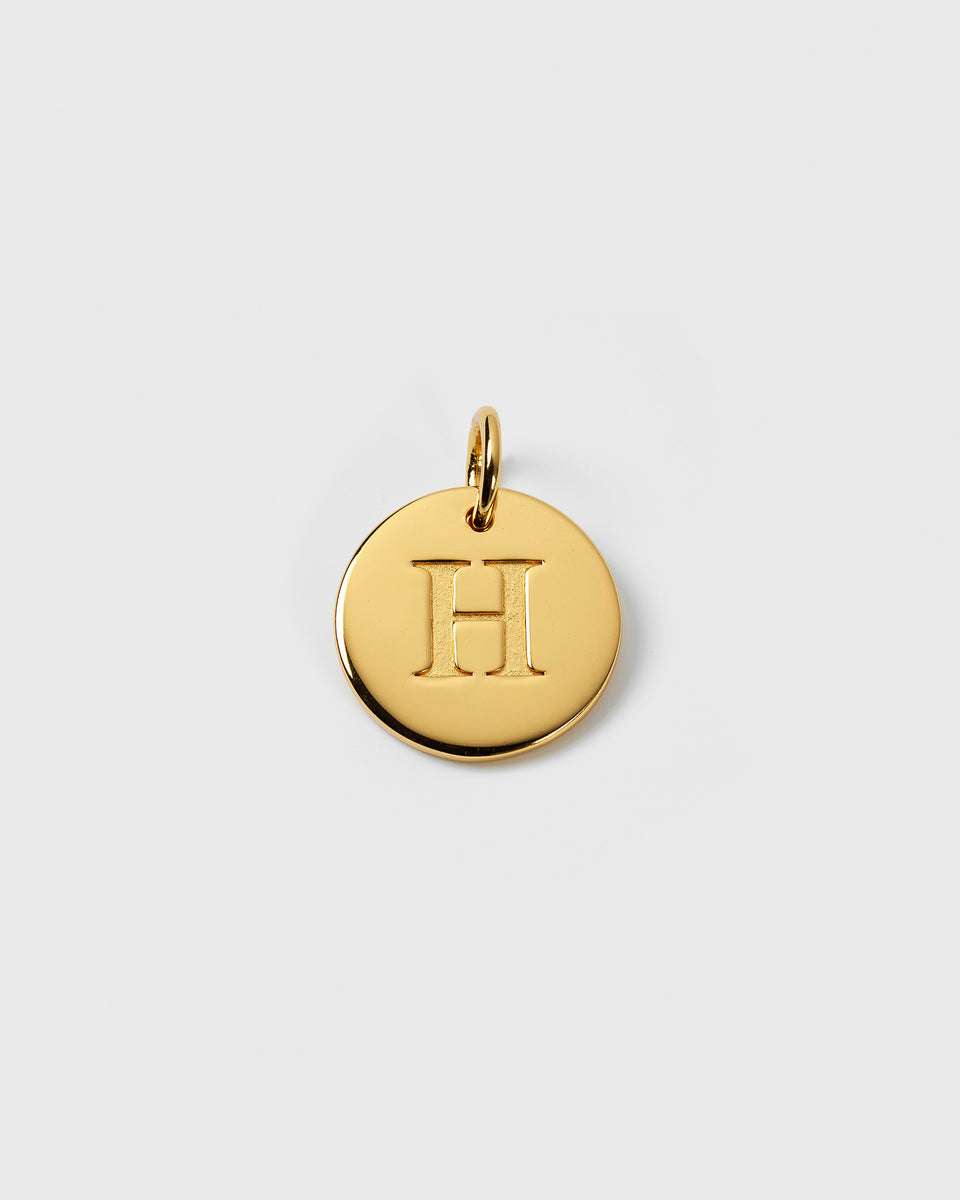 A product shot of the Beloved Big Letter charm in gold, featuring the letter H engraved on a round pendant.