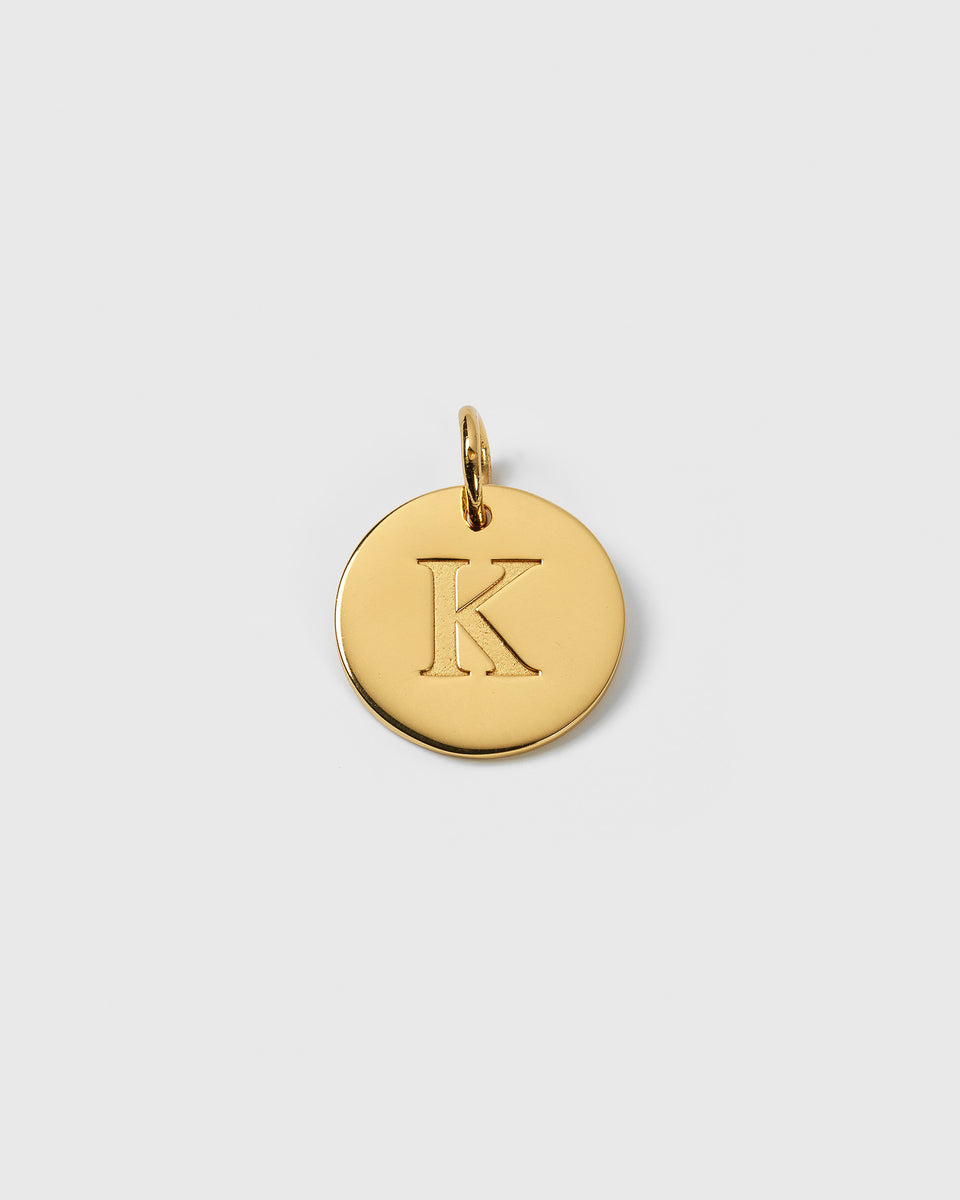 A product shot of the Beloved Big Letter Gold pendant, featuring the letter K engraved on a circular gold charm.