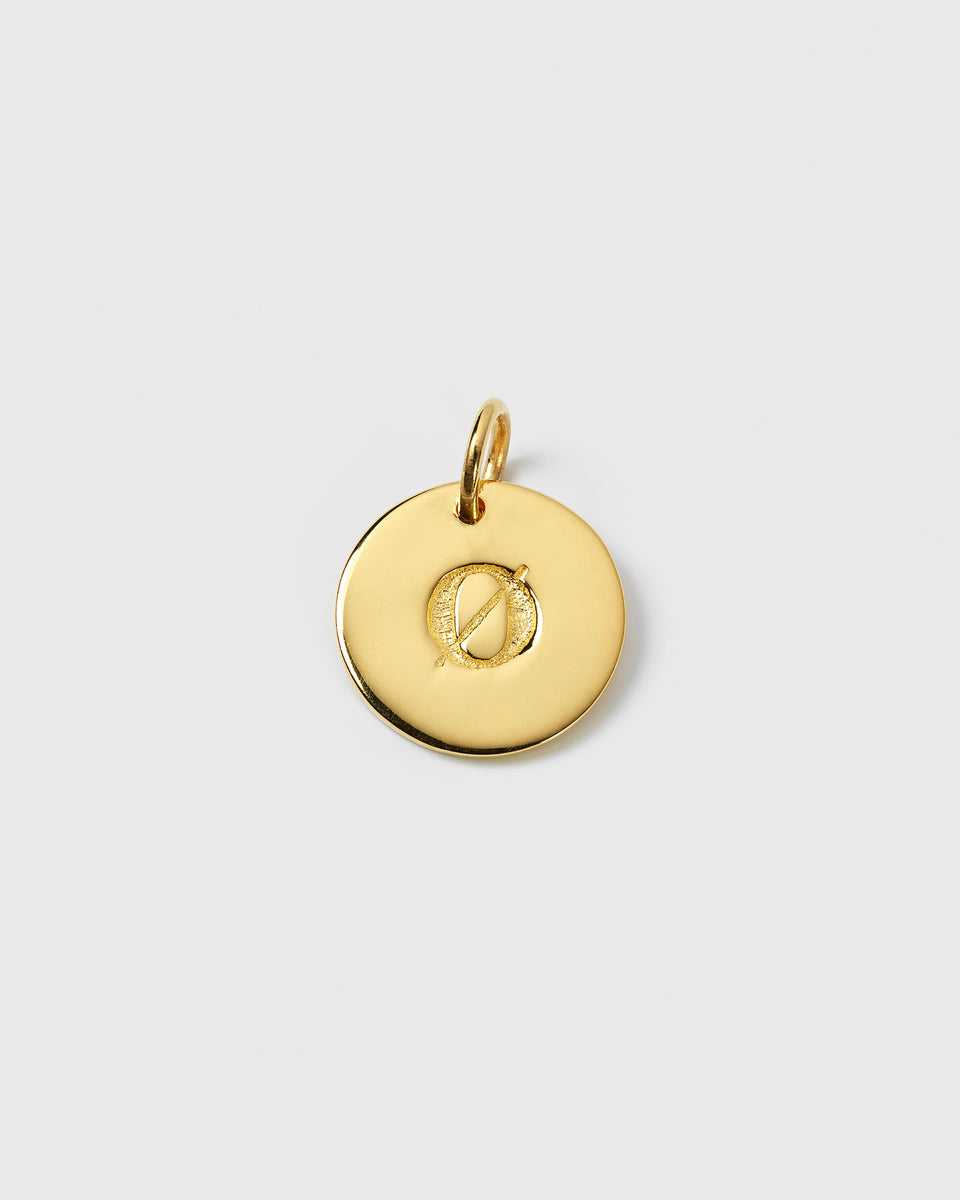 A close-up of the Beloved Big Letter Gold pendant, a round gold charm featuring a textured engraving of the letter 'Ø'.