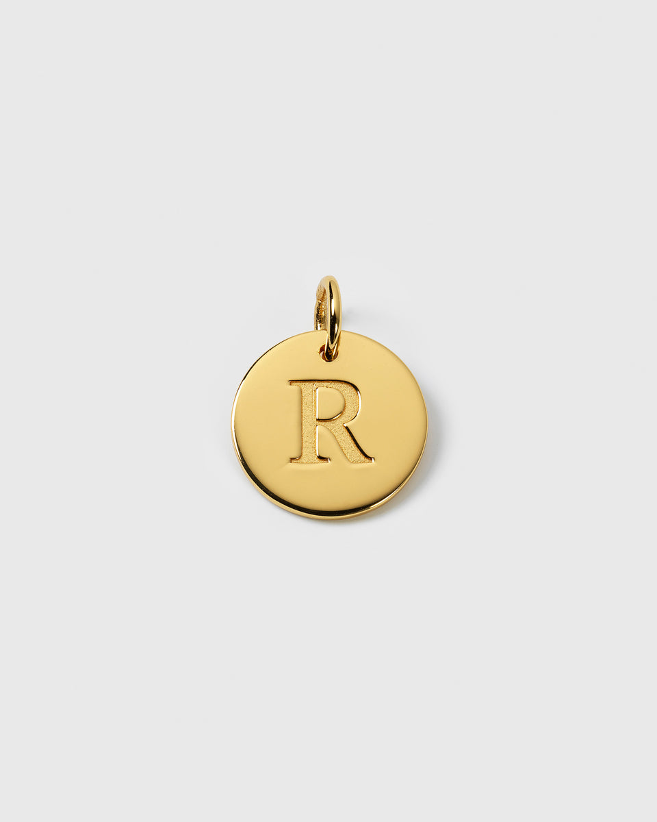 A close-up image of the gold Beloved Big Letter charm, showing the letter 'R' engraved on a circular pendant.