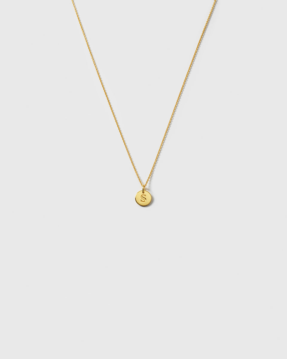 A product shot of the gold Beloved Short Oval Chain, styled with a small, circular pendant engraved with the letter 'S'.
