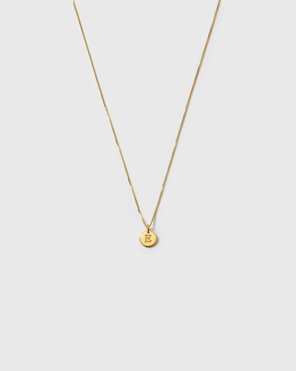 A product shot of the Beloved Medium Box Chain in gold, styled with a small, circular pendant engraved with the letter E.