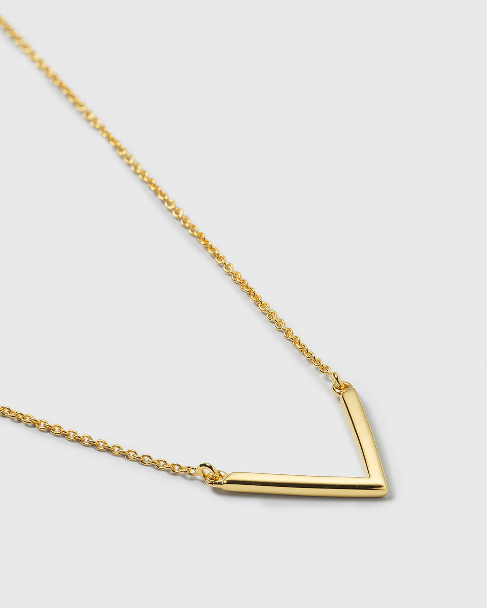 A product shot of the Strict V Necklace in gold, detailing the fine chain and the sleek, minimalist V-shaped pendant.