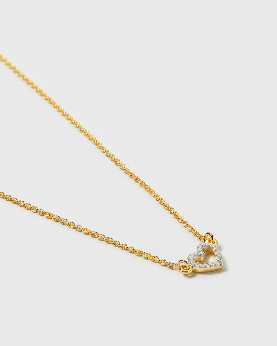 A product shot of the Snap Heart Necklace in gold, featuring a fine chain and an open heart-shaped pendant encrusted with clear crystal stones.