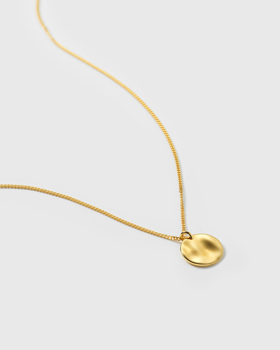A product shot of the Minimalistica Hammered Necklace in gold, featuring a fine chain and a circular pendant with a hammered surface.