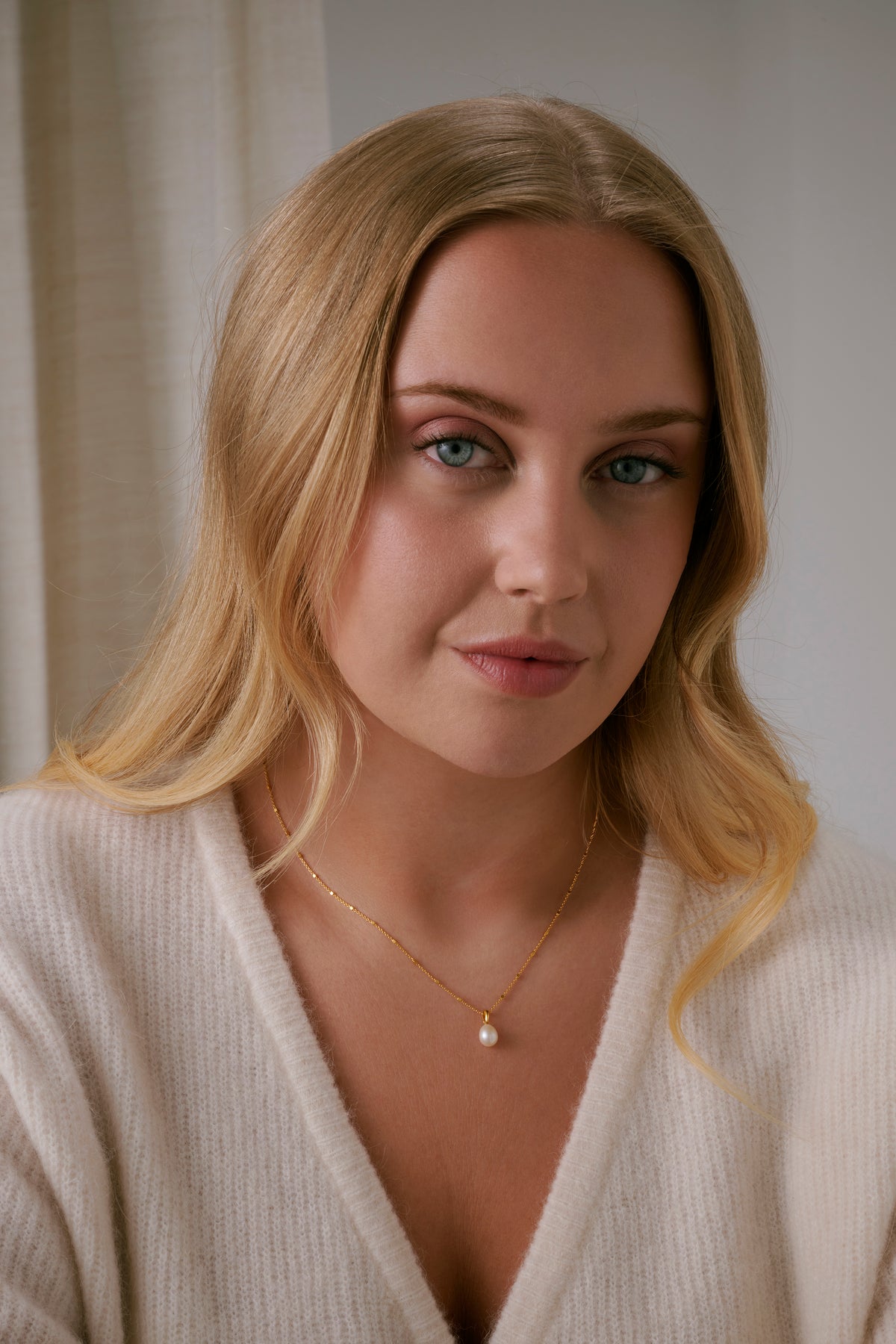 A model shot of the Treasure Single Pearl Necklace in gold, highlighting its unique chain and its single teardrop-shaped freshwater pearl pendant.