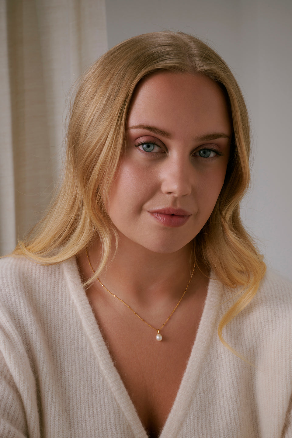 A model shot of the Treasure Single Pearl Necklace in gold, highlighting its unique chain and its single teardrop-shaped freshwater pearl pendant.