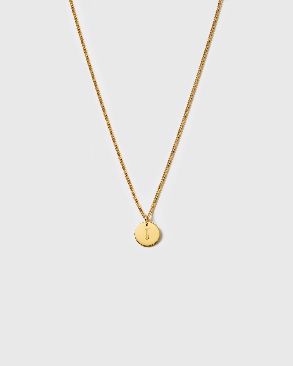 A product shot of the Beloved Short Curb Chain in gold, shown with a round pendant engraved with the letter I.