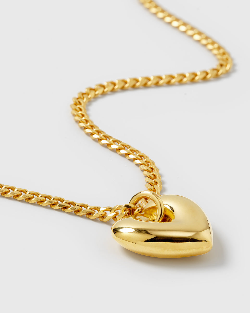 A close-up product shot of the Fat Heart Necklace in gold, highlighting its chunky chain and large, puffy heart pendant.