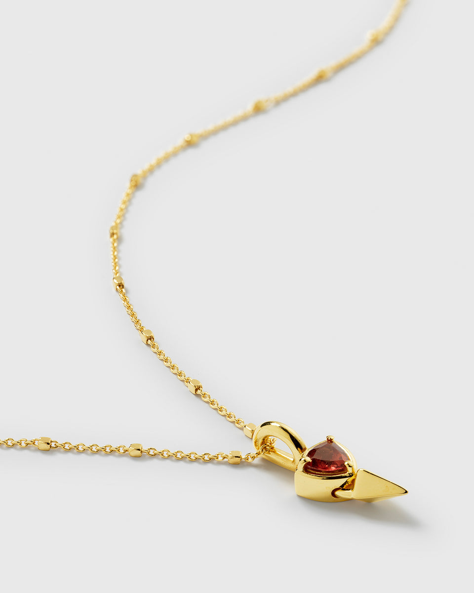 A close-up of the Mrs H Spike Necklace in gold, showcasing the detailed pendant with its sharp spike and set red garnet, hanging from a delicate beaded chain.
