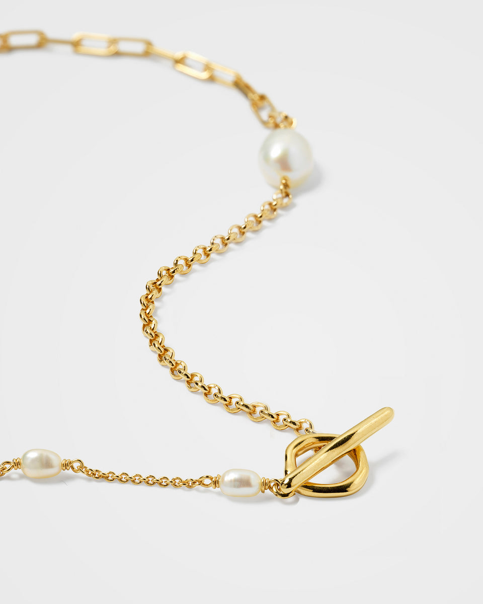 Close-up of the Paxton Short Necklace in gold, showing the intricate details of its mixed chains, freshwater pearls, and toggle clasp.