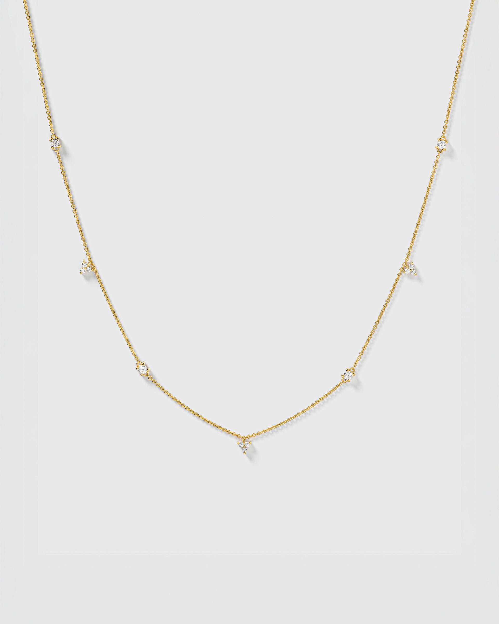 A product shot of the Celestia Necklace in gold, featuring a delicate chain with sparkling cubic zirconia stones set at intervals.