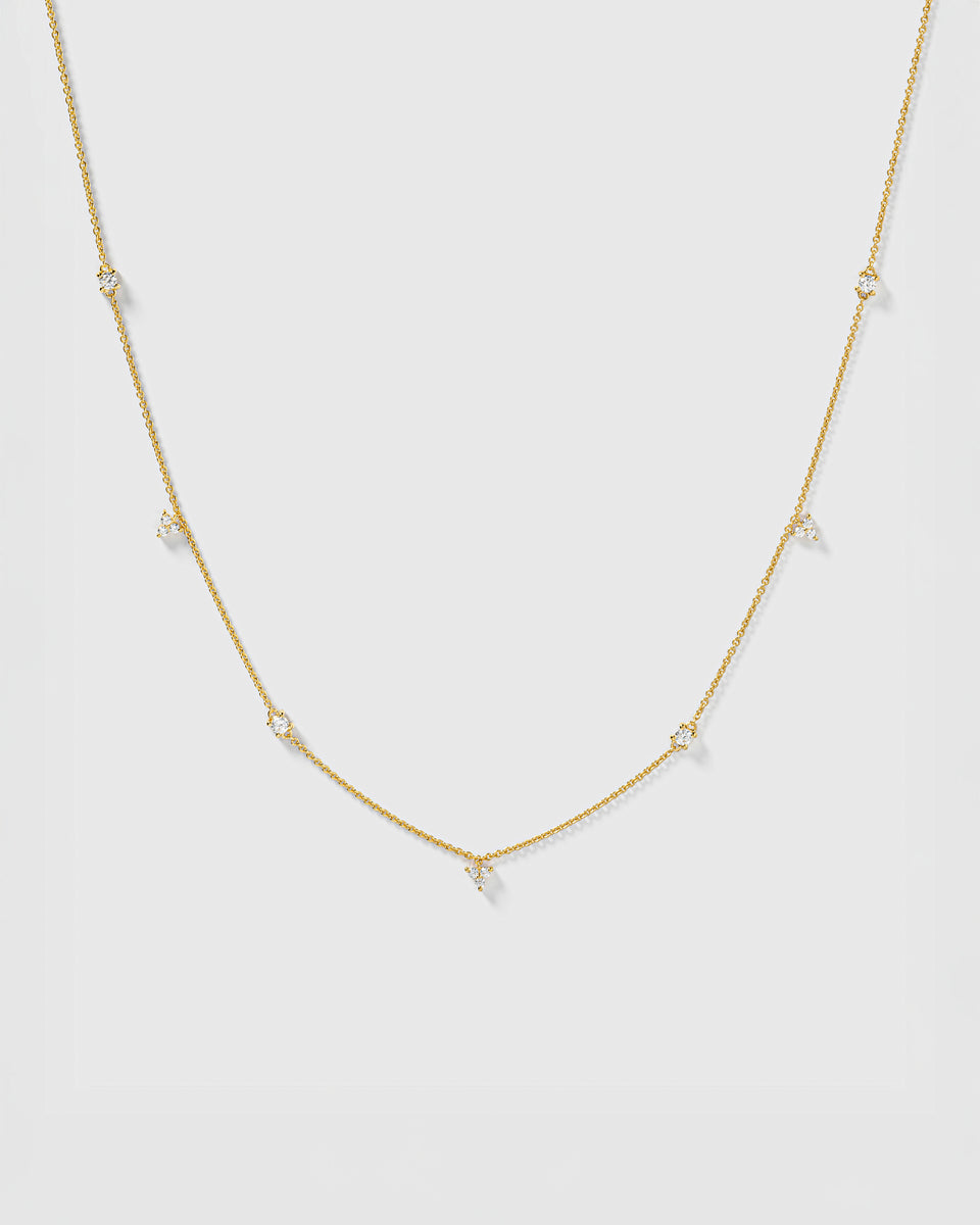 A product shot of the Celestia Necklace in gold, featuring a delicate chain with sparkling cubic zirconia stones set at intervals.