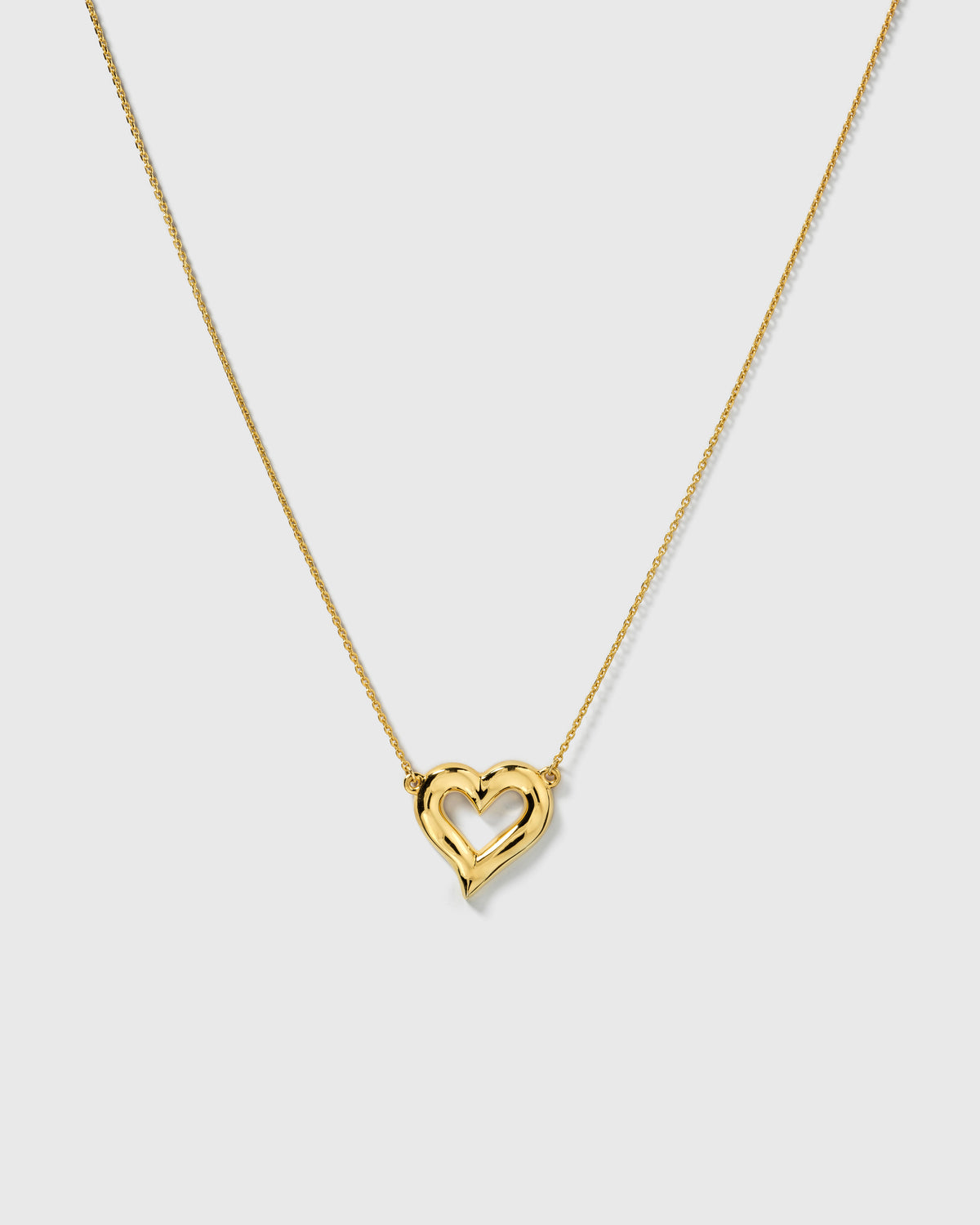 A product shot of the Puff Heart Necklace in gold, showcasing its chunky and organic heart-shaped pendant on a delicate chain.