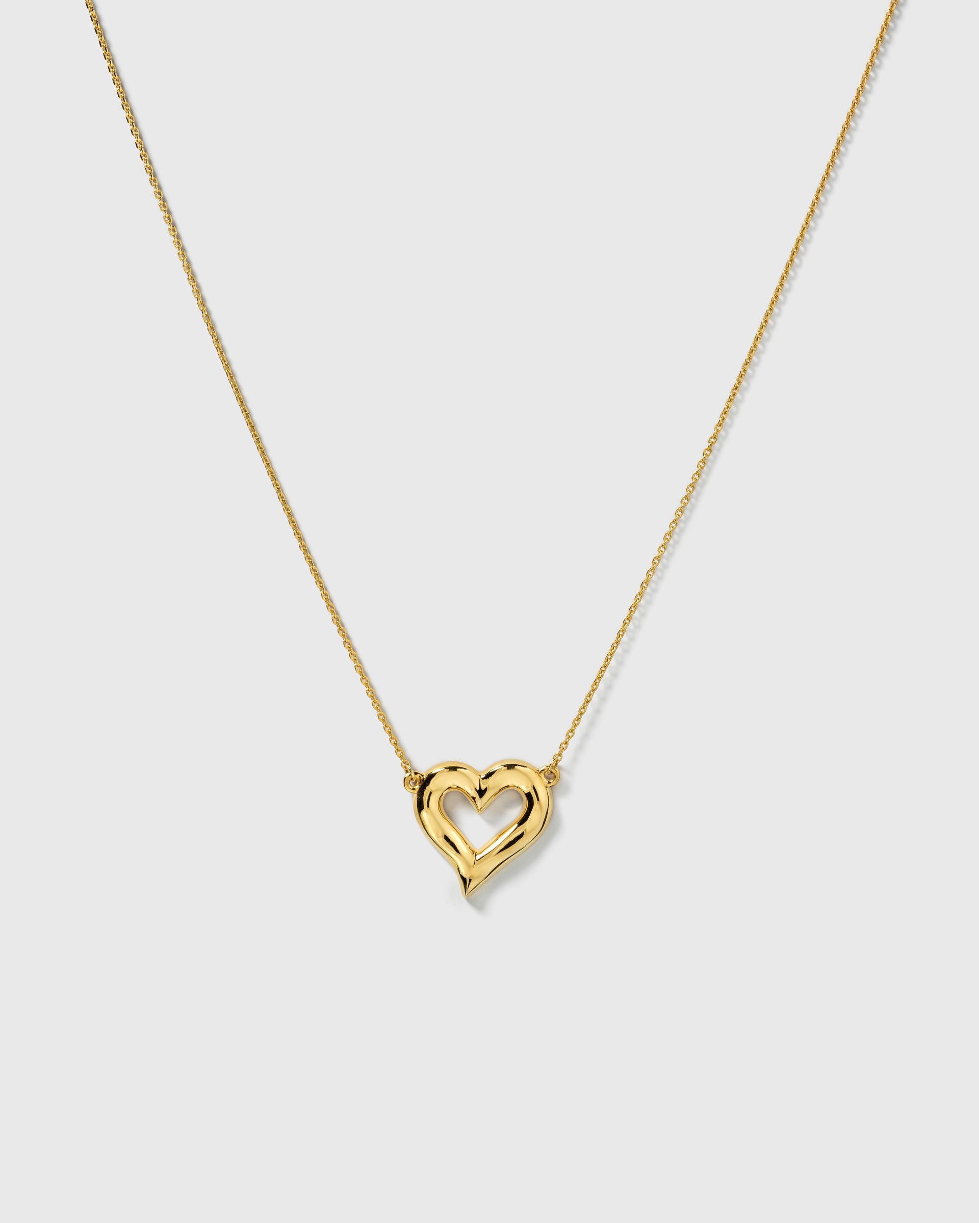 A product shot of the Puff Heart Necklace in gold, showcasing its chunky and organic heart-shaped pendant on a delicate chain.